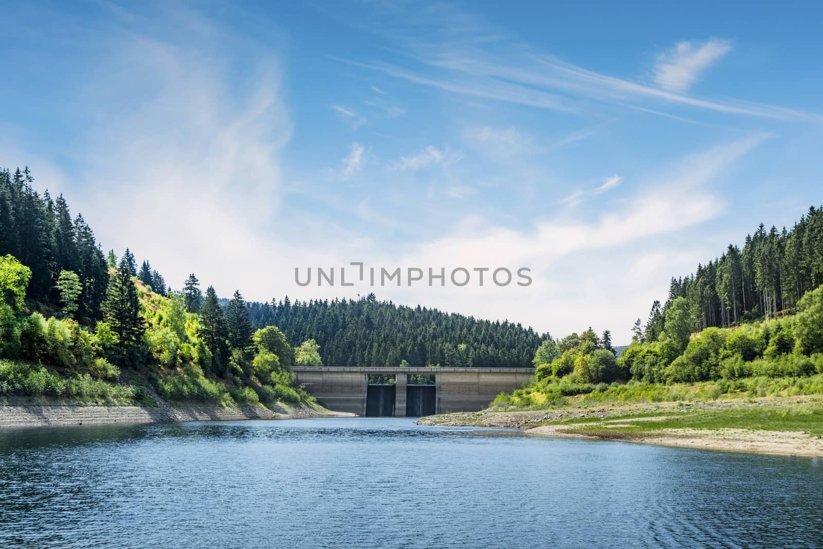 Dam in a colorful landscape in the summer on a lake surrounded by forest