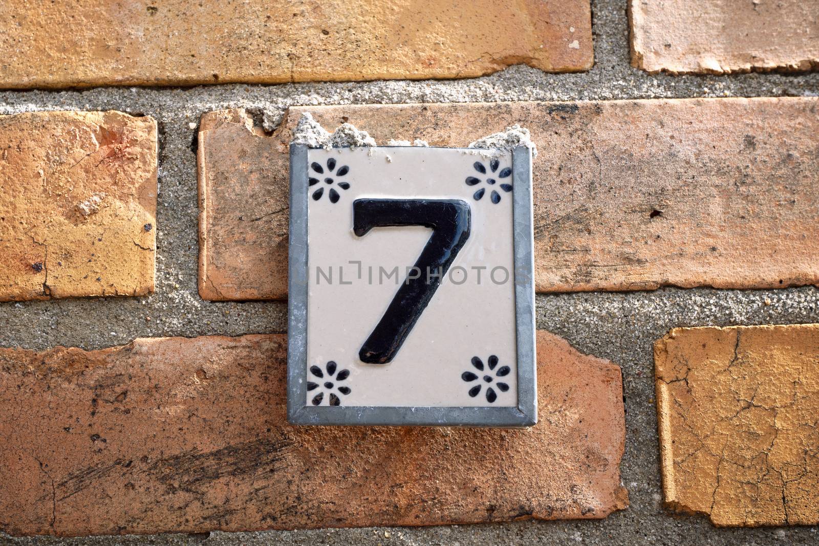 Sign with the number 7 house number hanging on a brick wall 