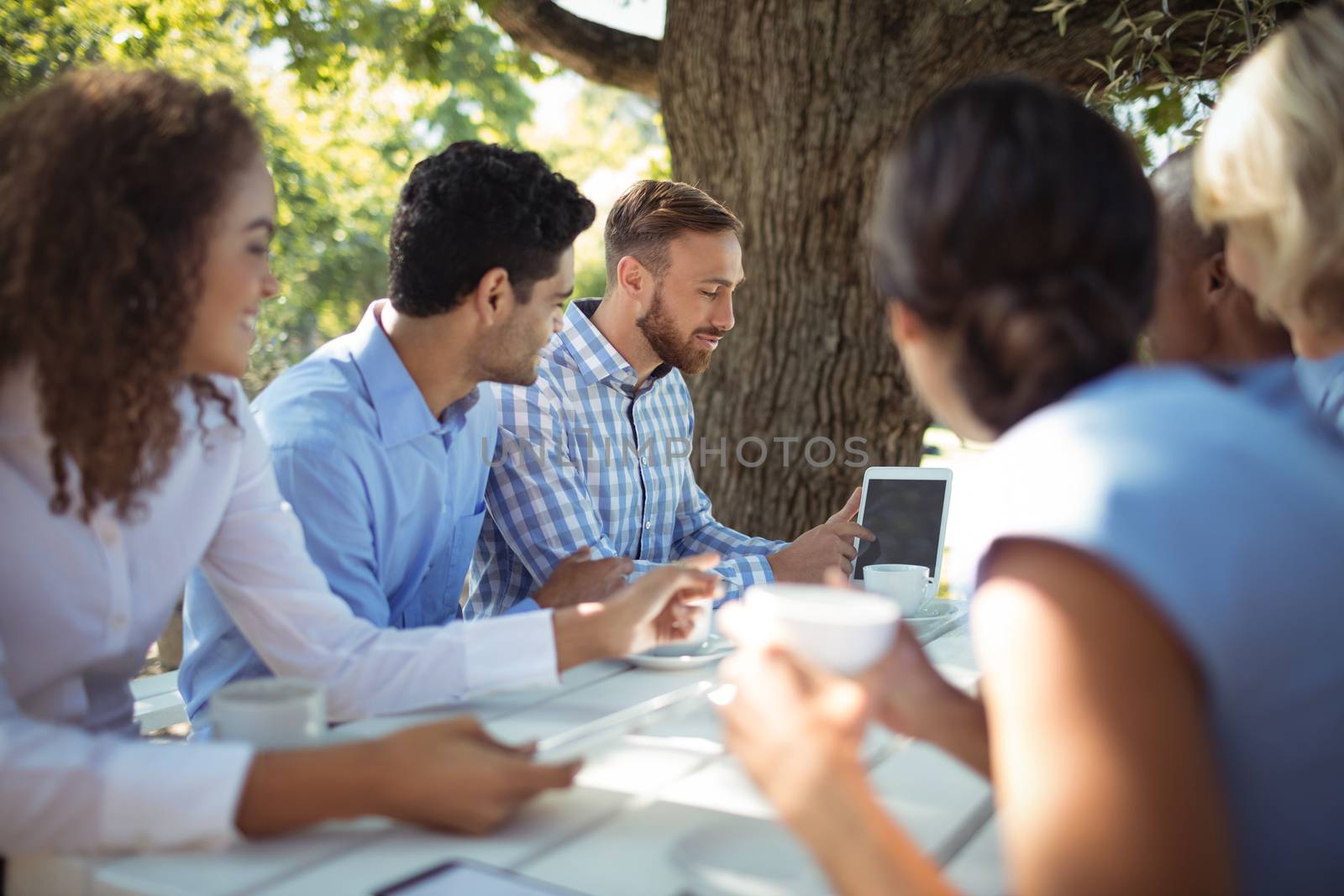 Group of friends interacting with each other in outdoors restaurant