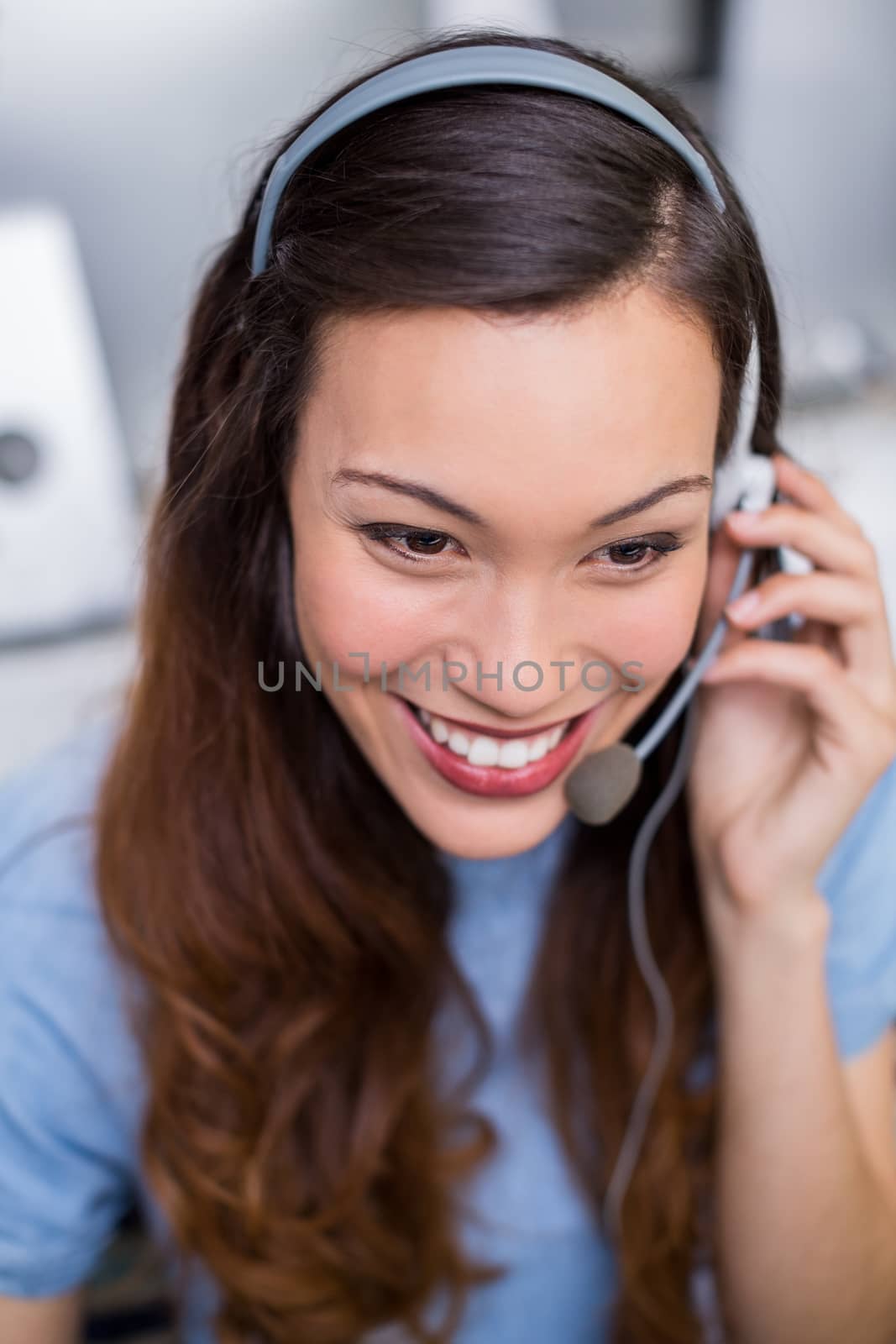 Smiling female customer service executive talking on headset at desk in office