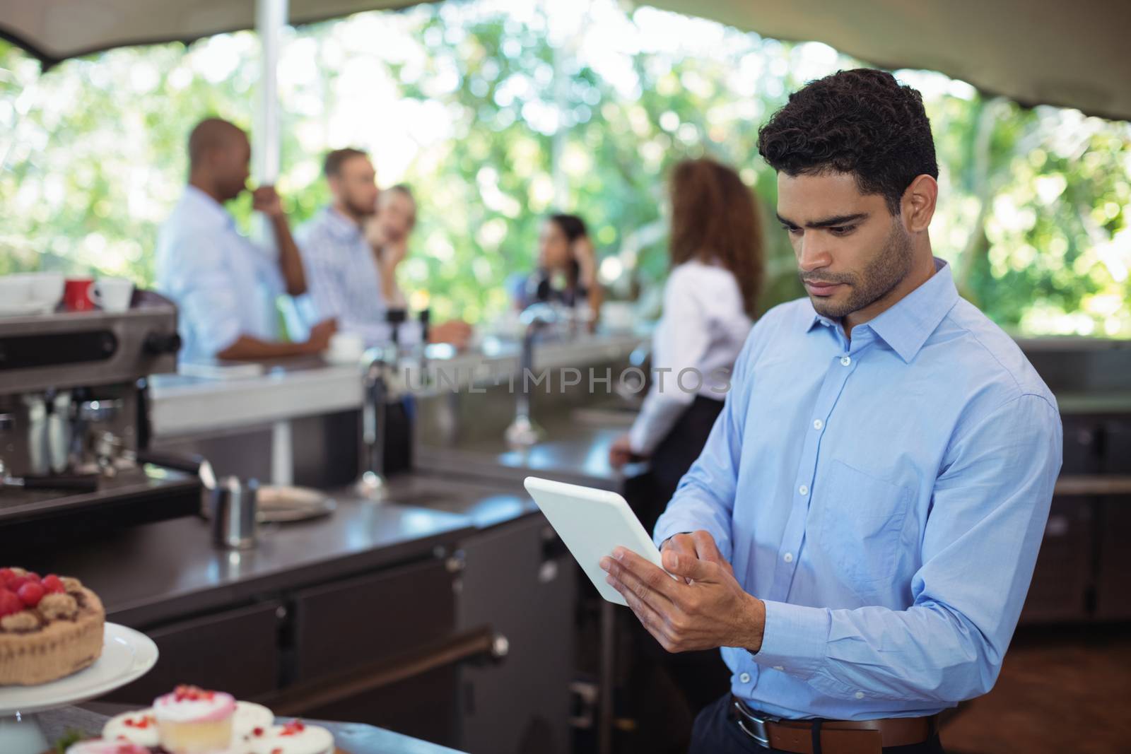 Young waiter using digital tablet at outdoors cafe
