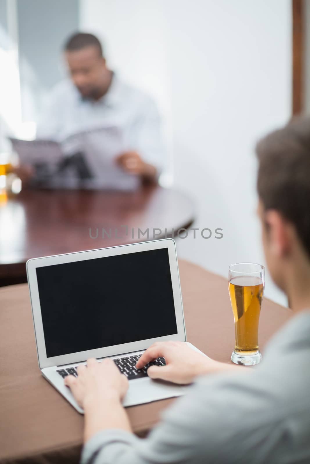 Rear view of man using laptop in the restaurant