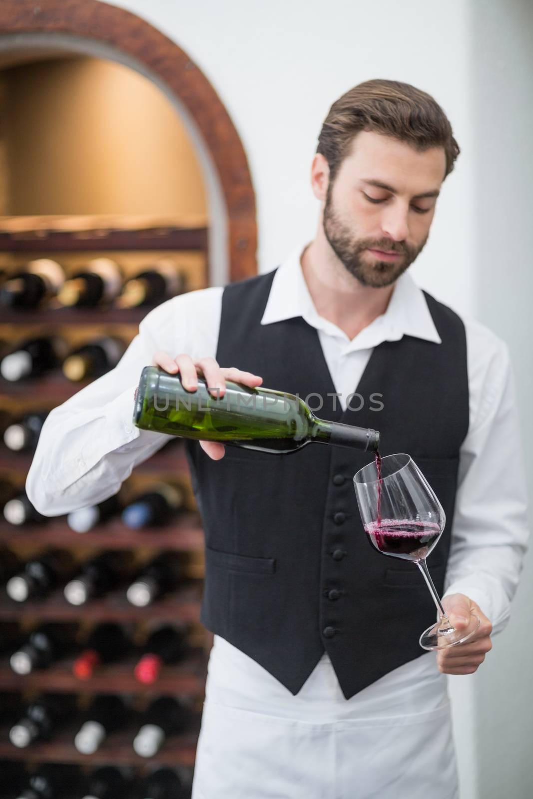 Male waiter pouring wine in wine glass by Wavebreakmedia