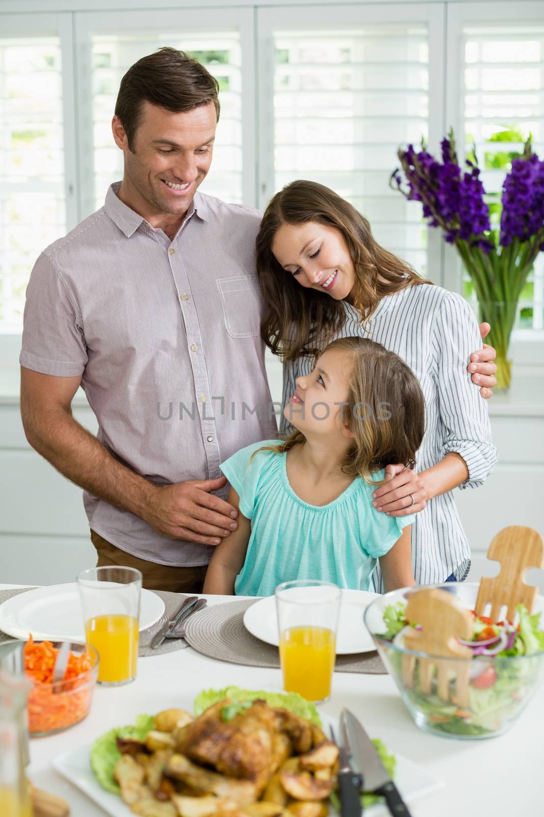 Smiling family interacting with each other while having lunch together by Wavebreakmedia