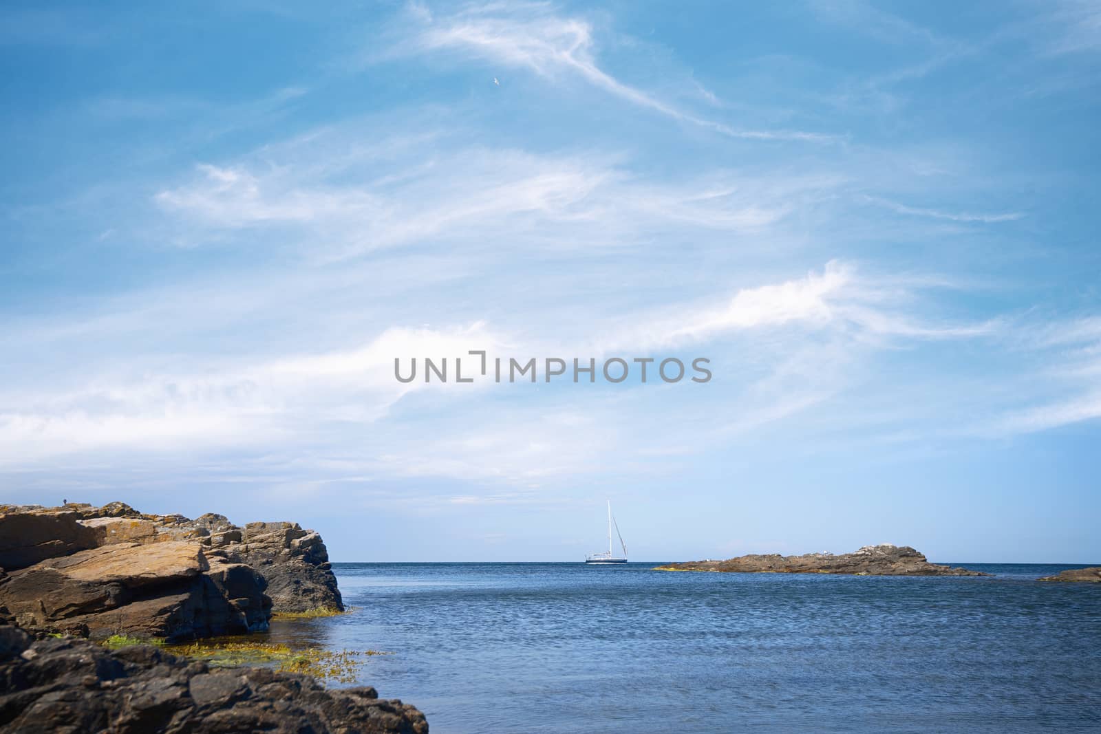 Sailboat on the sea under a blue sky with cliffs by the shore in the summer