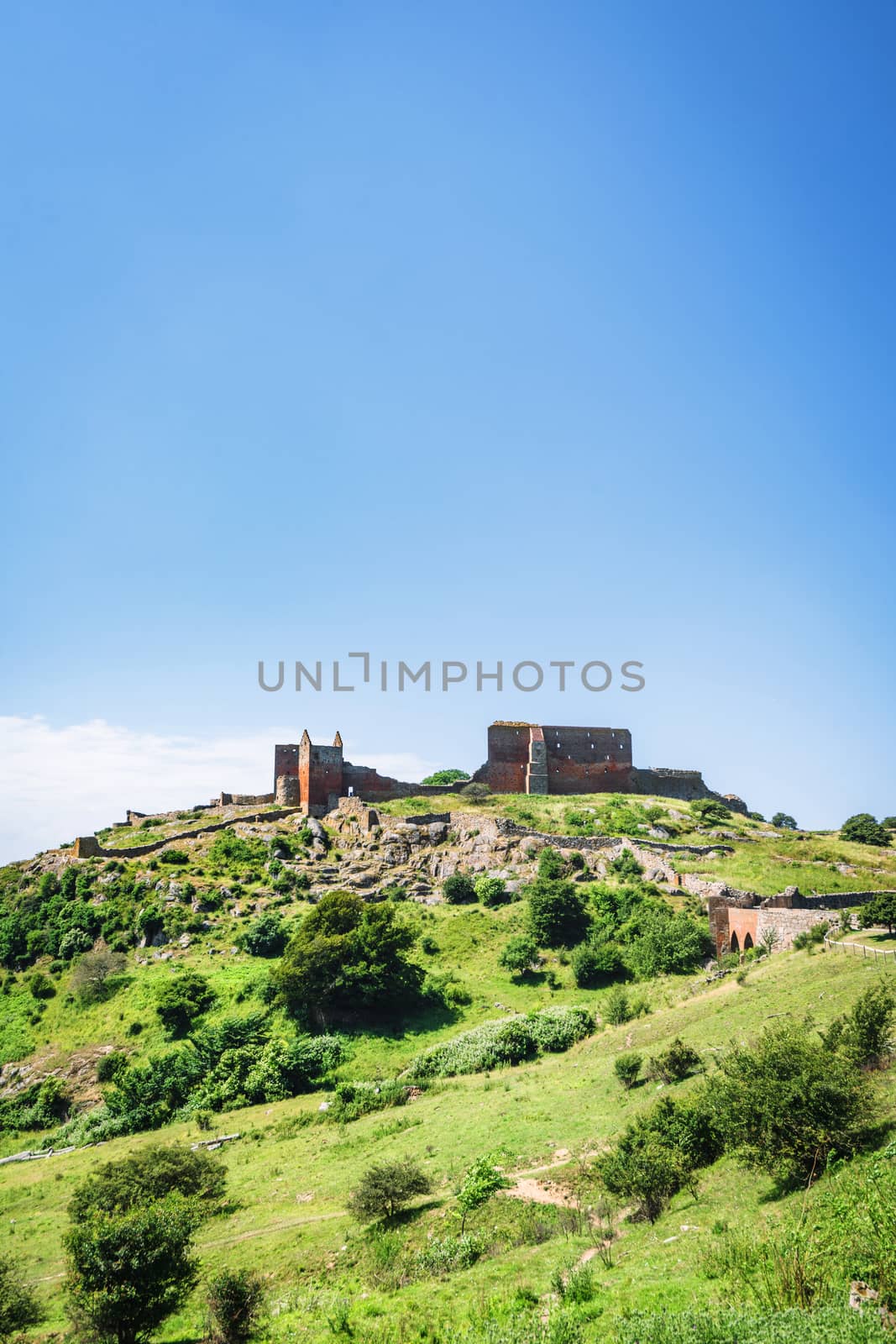 Castle ruin in a green landscape under a blue sky in the summer