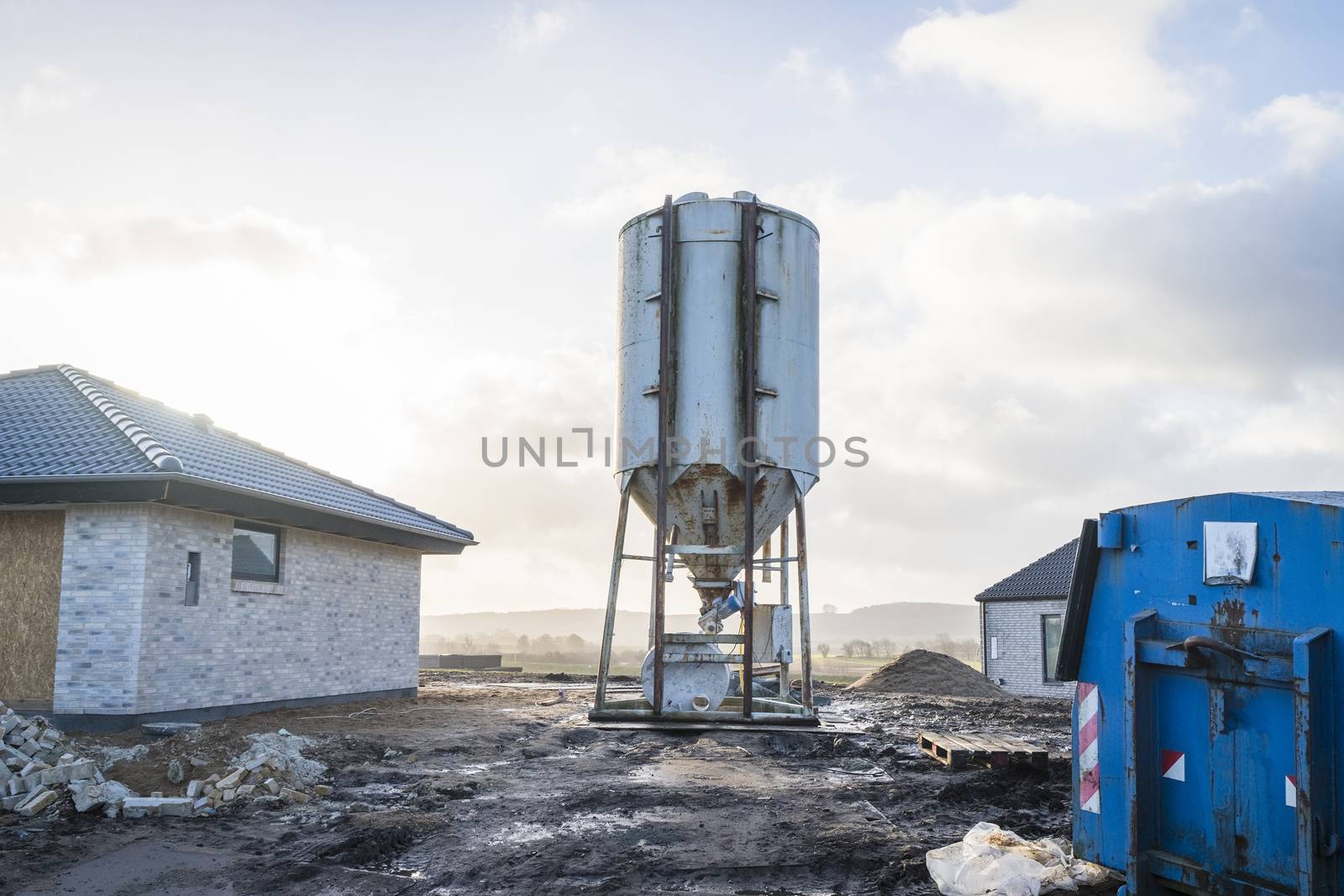 Silo at a construction area with new houses and a blue container