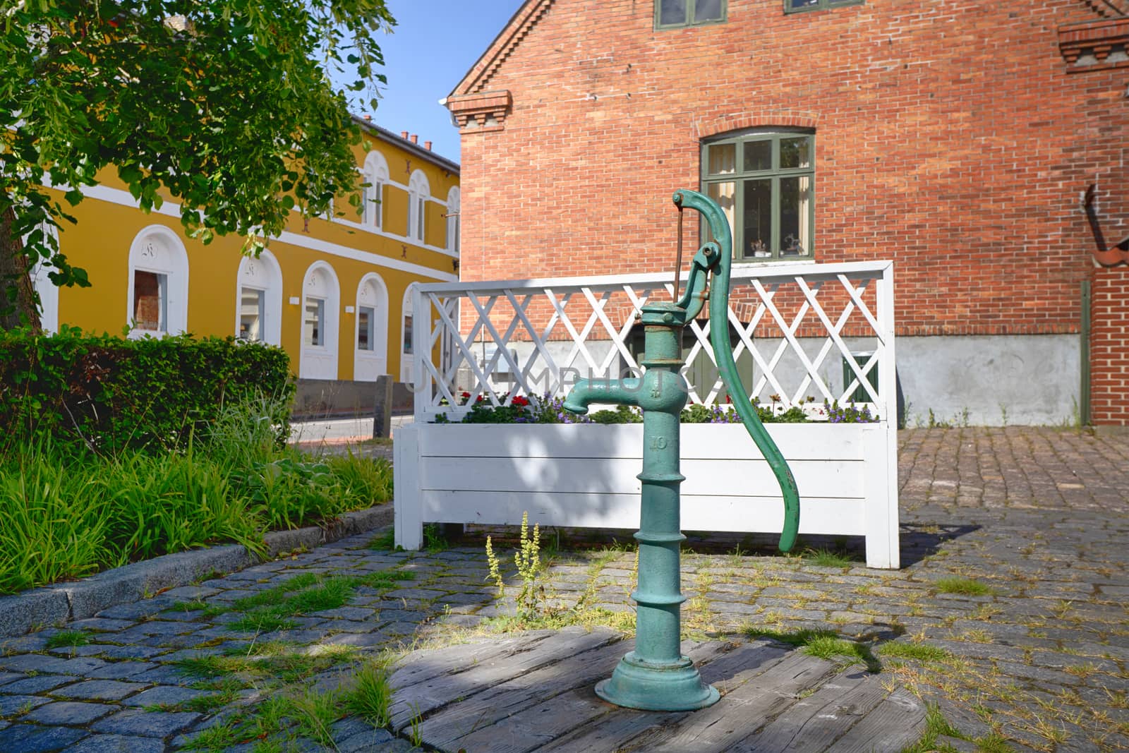 Turquoise fire hydrant on a street with colorful buildings on a summer day