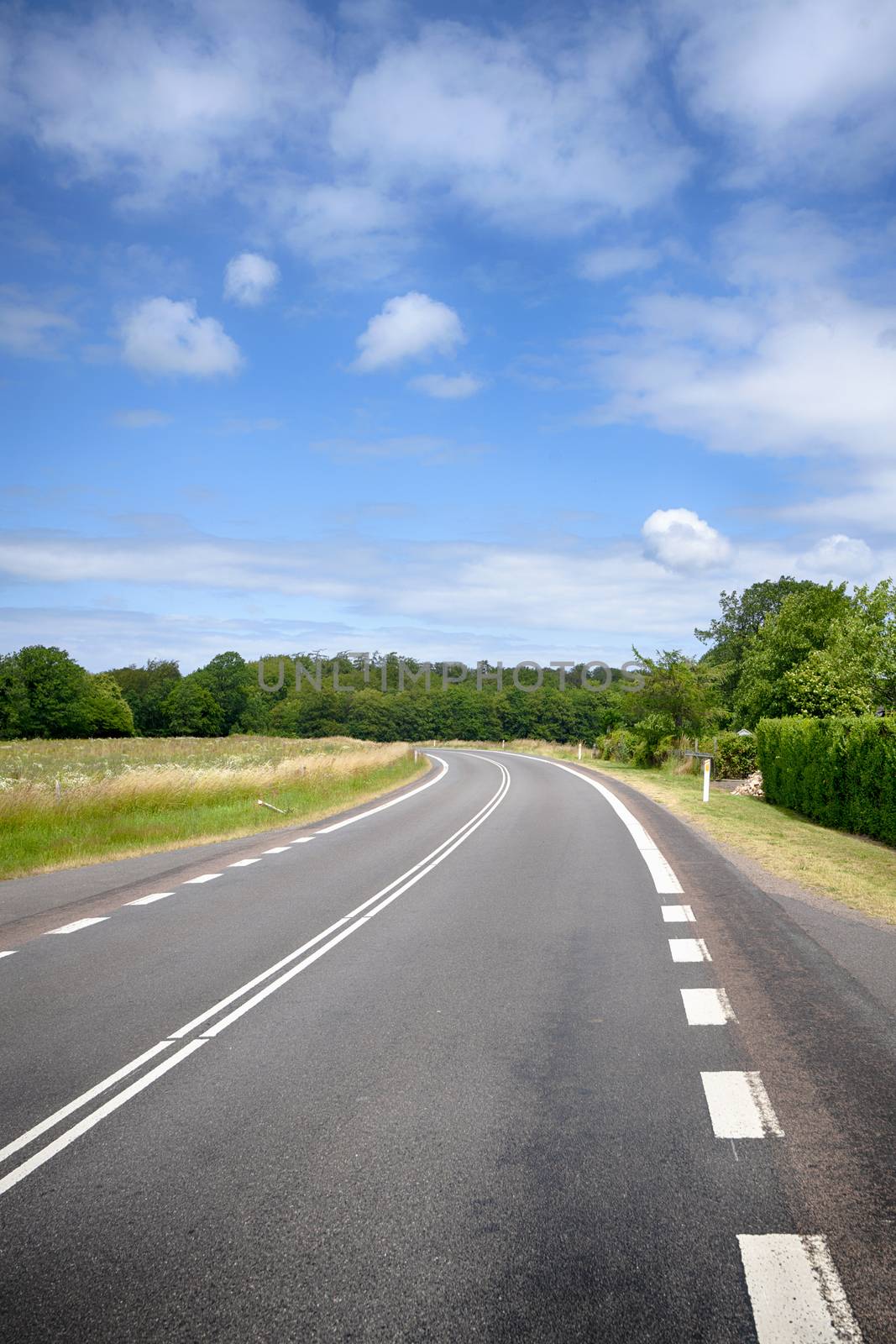 Curvy road in a rural countryside landscape under a blue sky in the summer