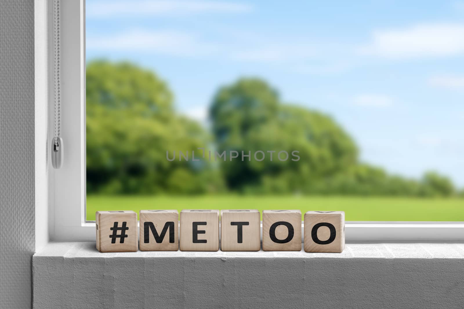 Metoo hashtag sign in a window with a view to green fields in the summer