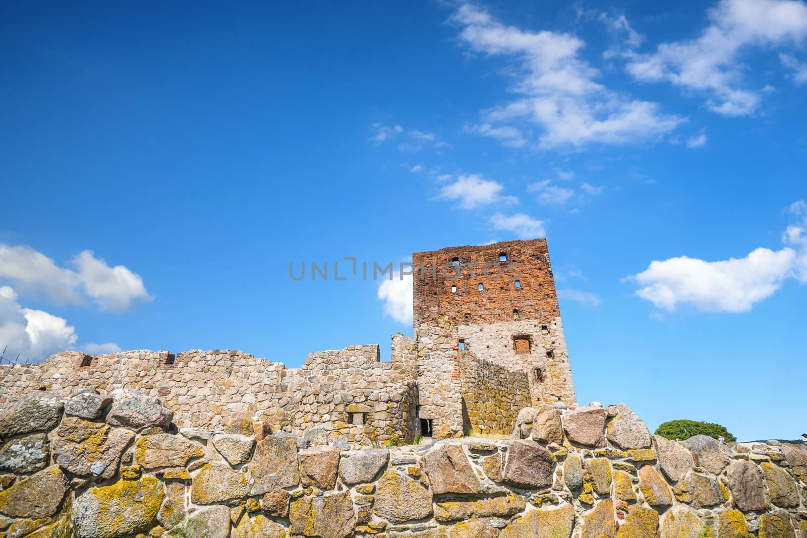 Castle ruin rising up behind an old brick wall by Sportactive