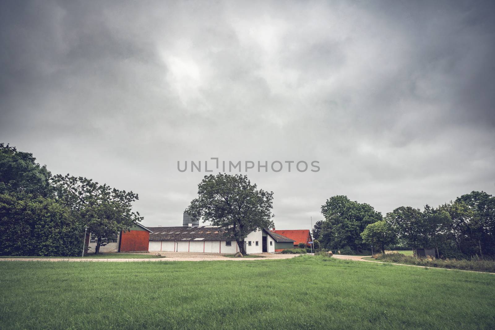 Rural landscape with a farm under a dramatic cloudy sky waiting for the rain