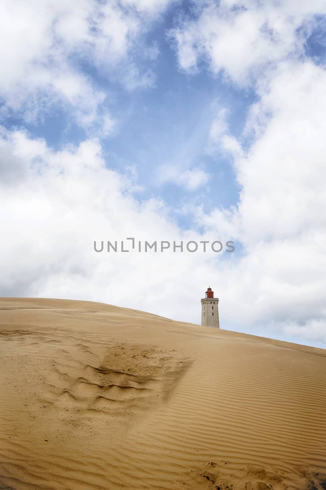 Lighthouse rising up behind a sand dune by Sportactive