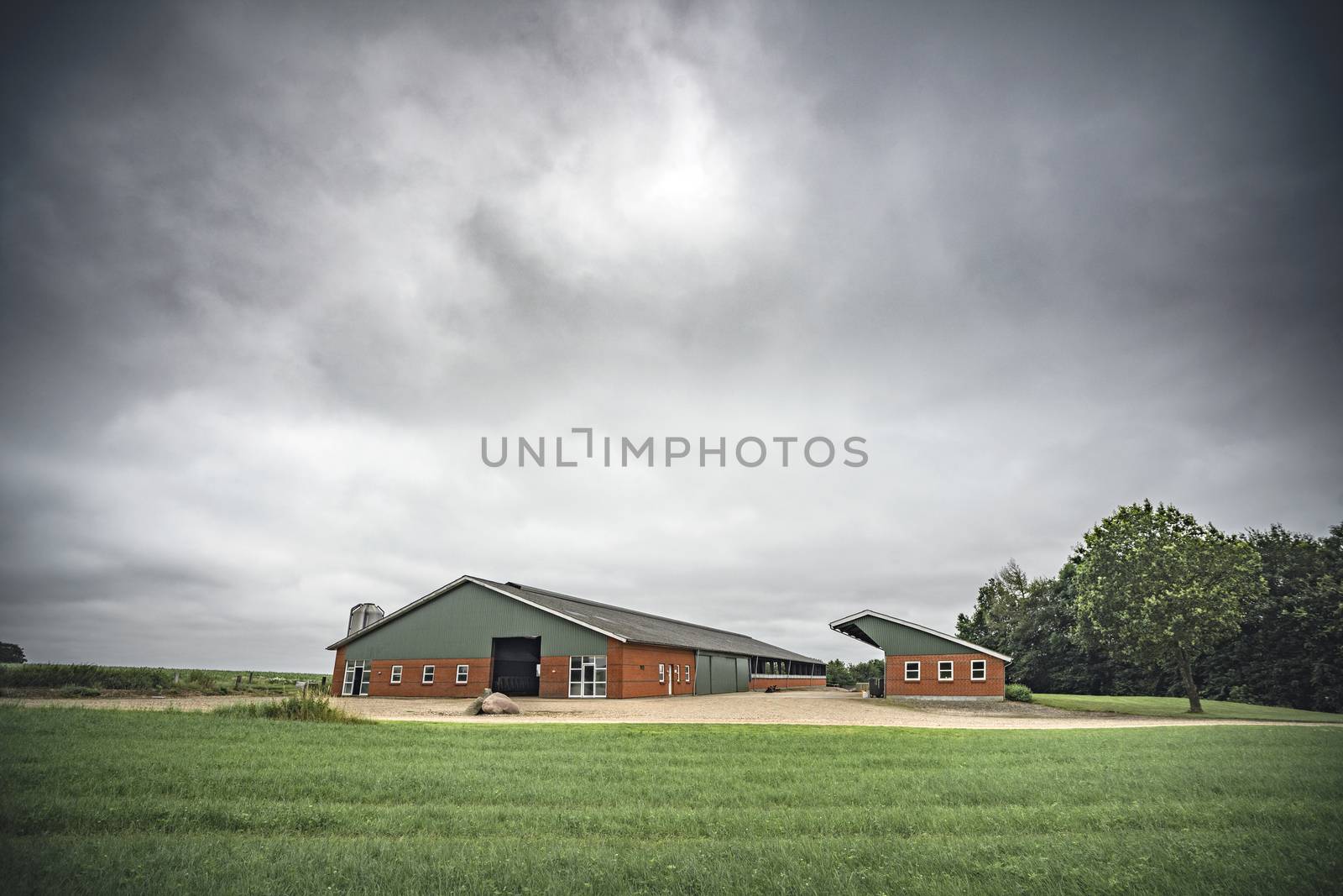 Farm under a cloudy sky with green fields by Sportactive