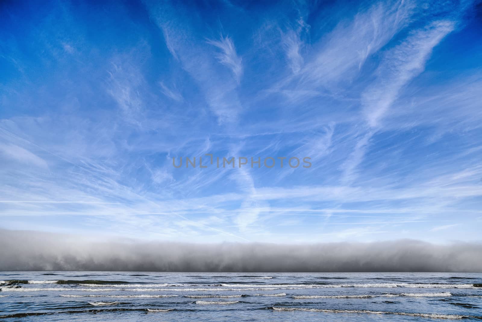 Cloudy weather over the ocean coming towards the shore under a blue sky