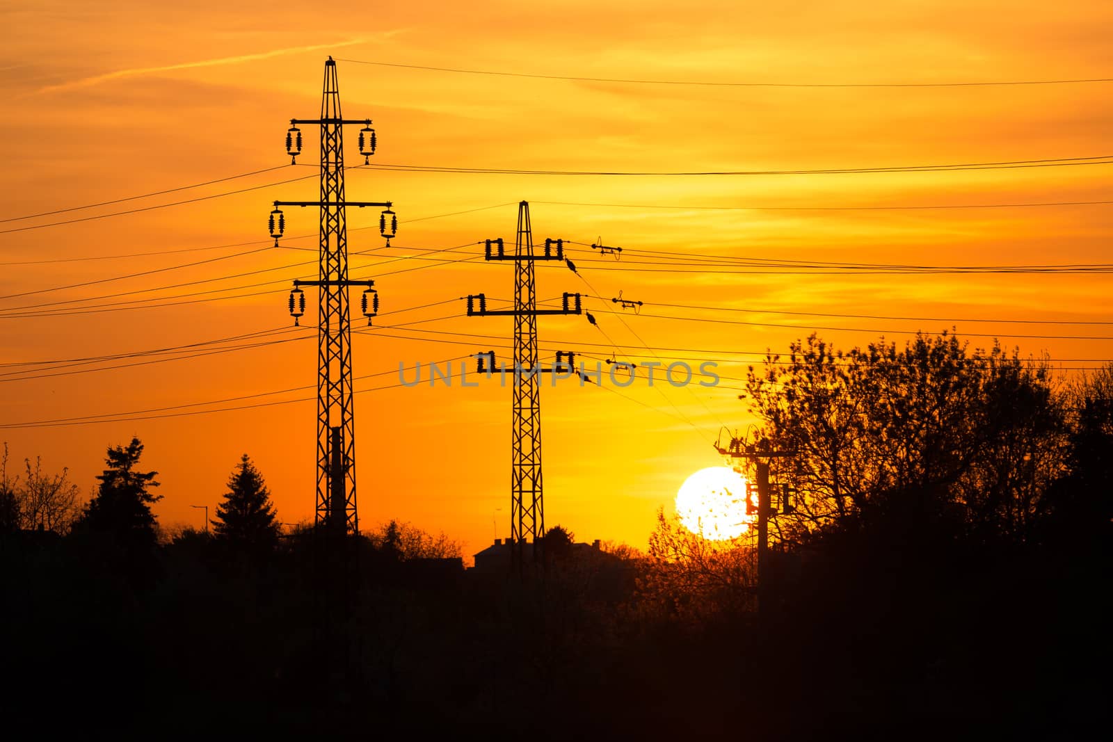 Silhouetted electric pylon with power line at sunset. reflection in water. by petrsvoboda91