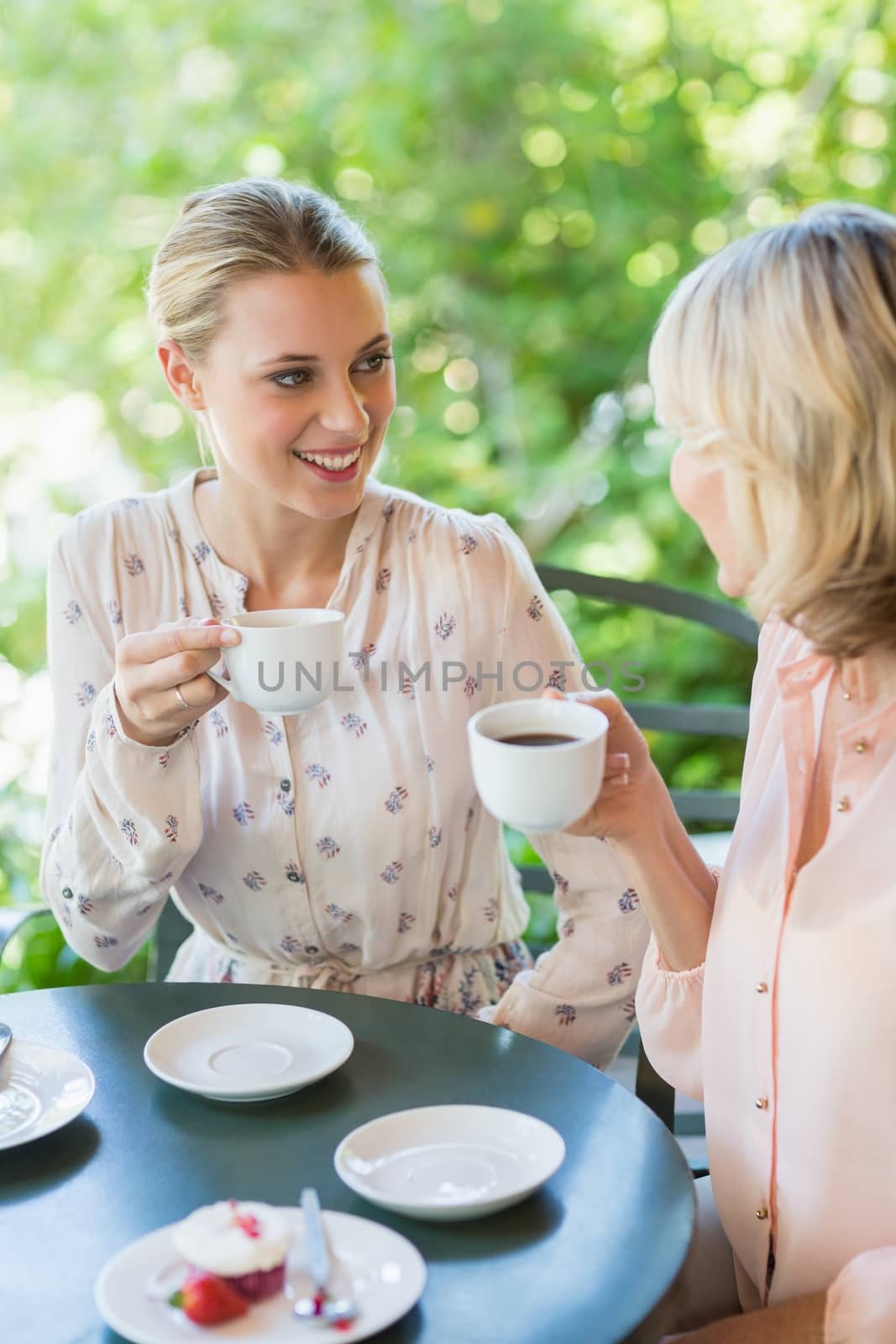 Smiling friends enjoying coffee together at restaurant