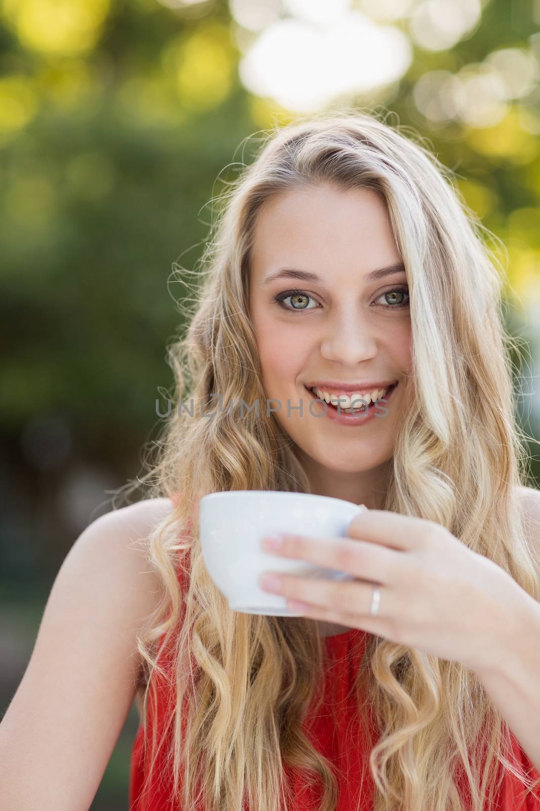 Beautiful woman smiling while having coffee by Wavebreakmedia