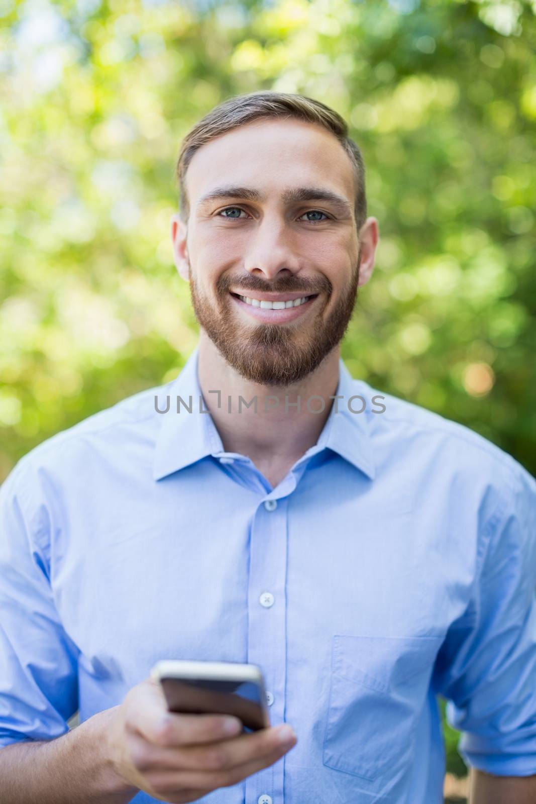 Portrait of man holding mobile phone in a park