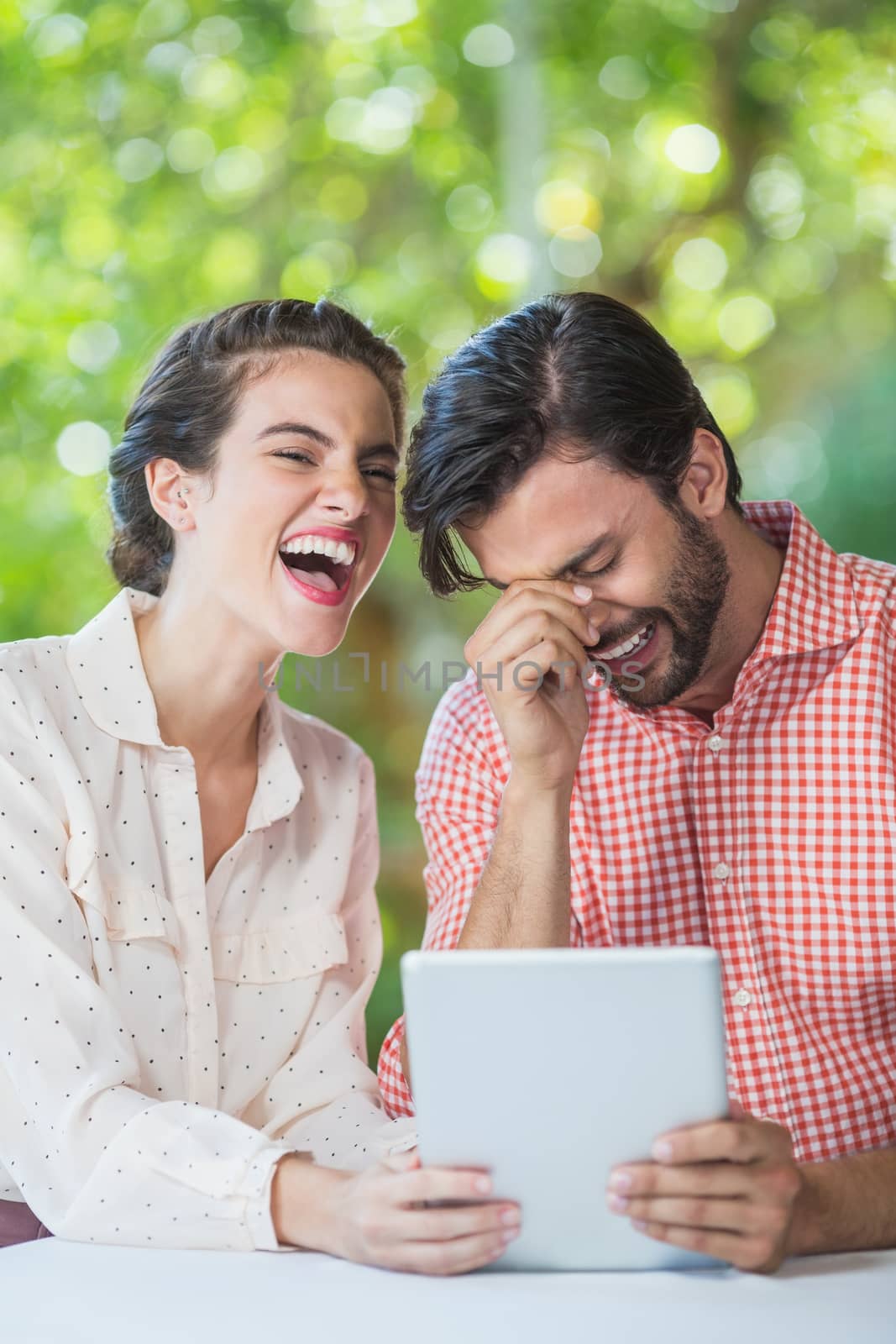 Couple laughing while using digital tablet by Wavebreakmedia