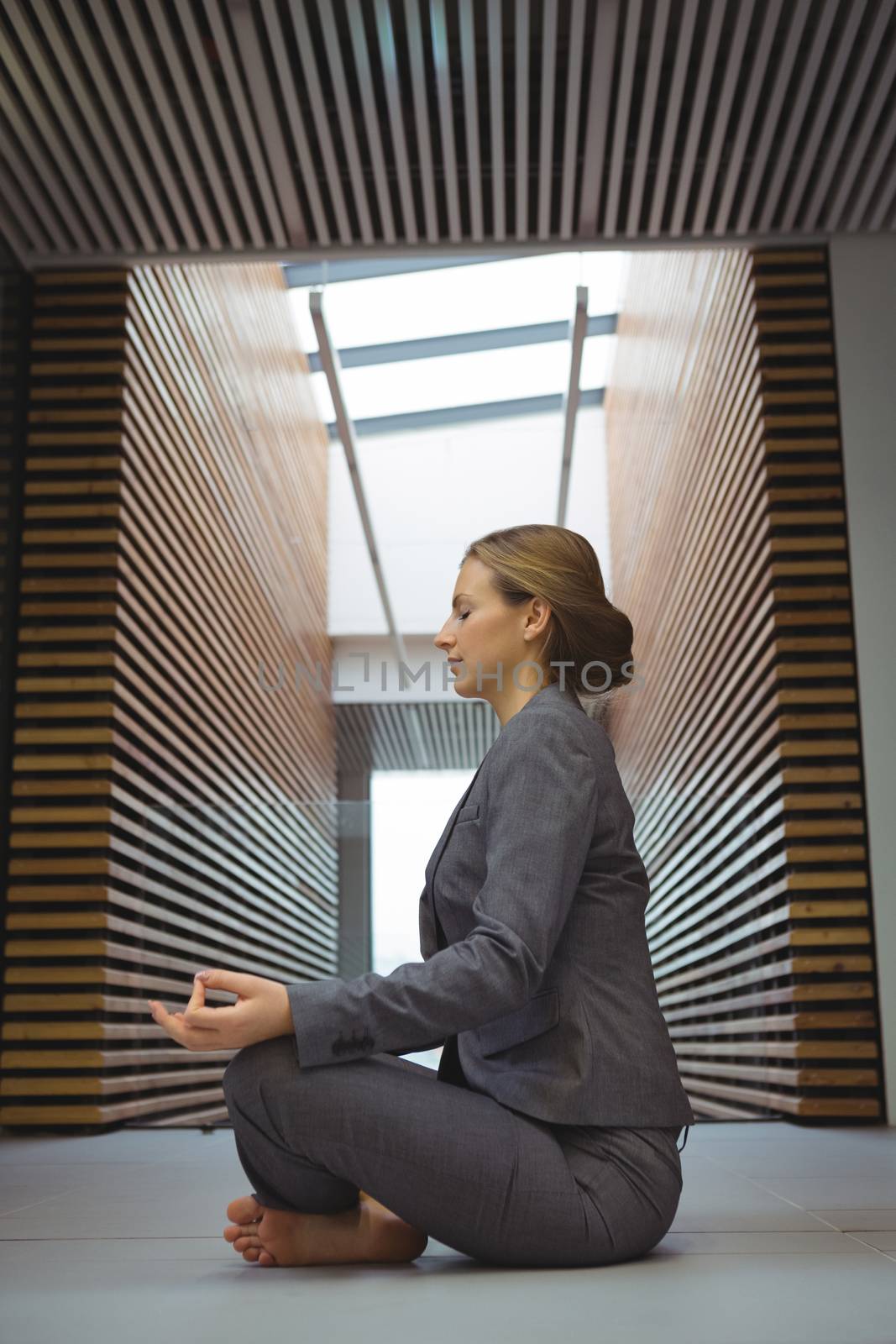 Businesswoman performing yoga in the corridor by Wavebreakmedia