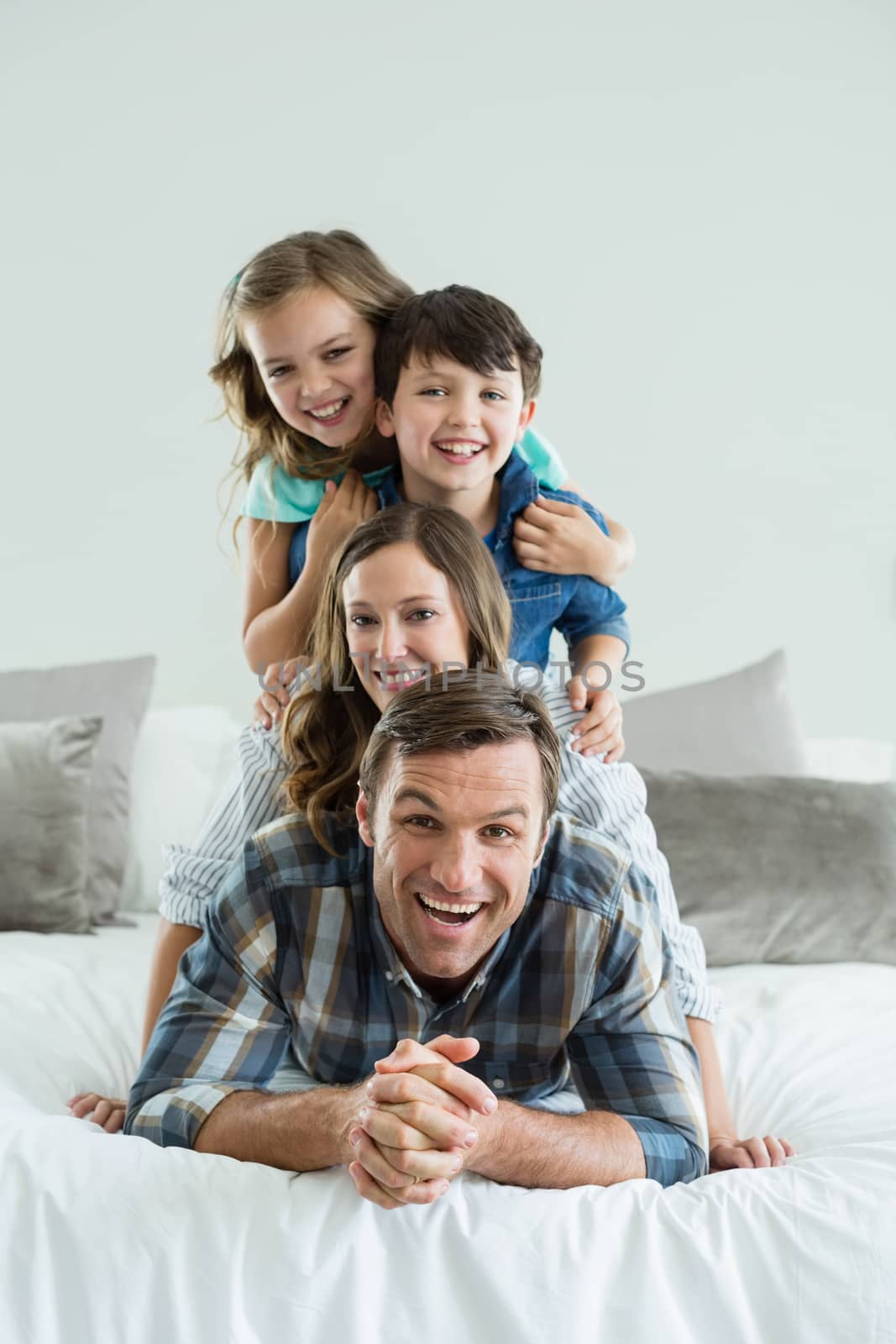 Portrait of smiling family playing on bed in bedroom by Wavebreakmedia