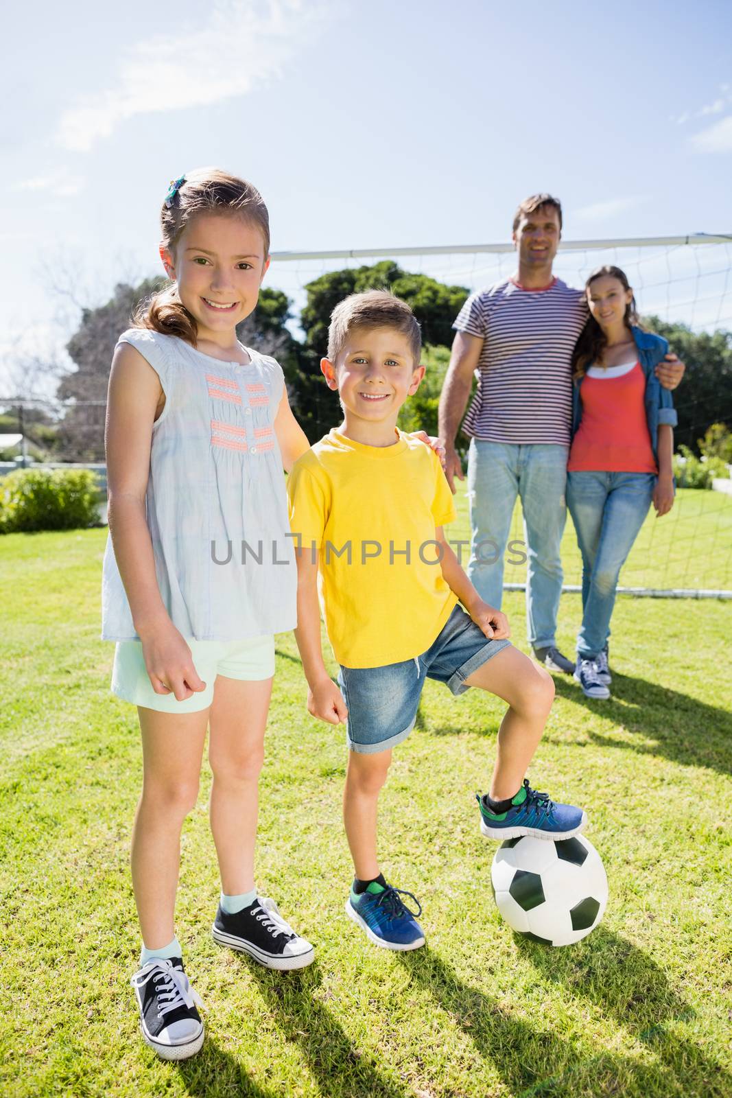 Portrait of happy family playing football in the park on a sunny day