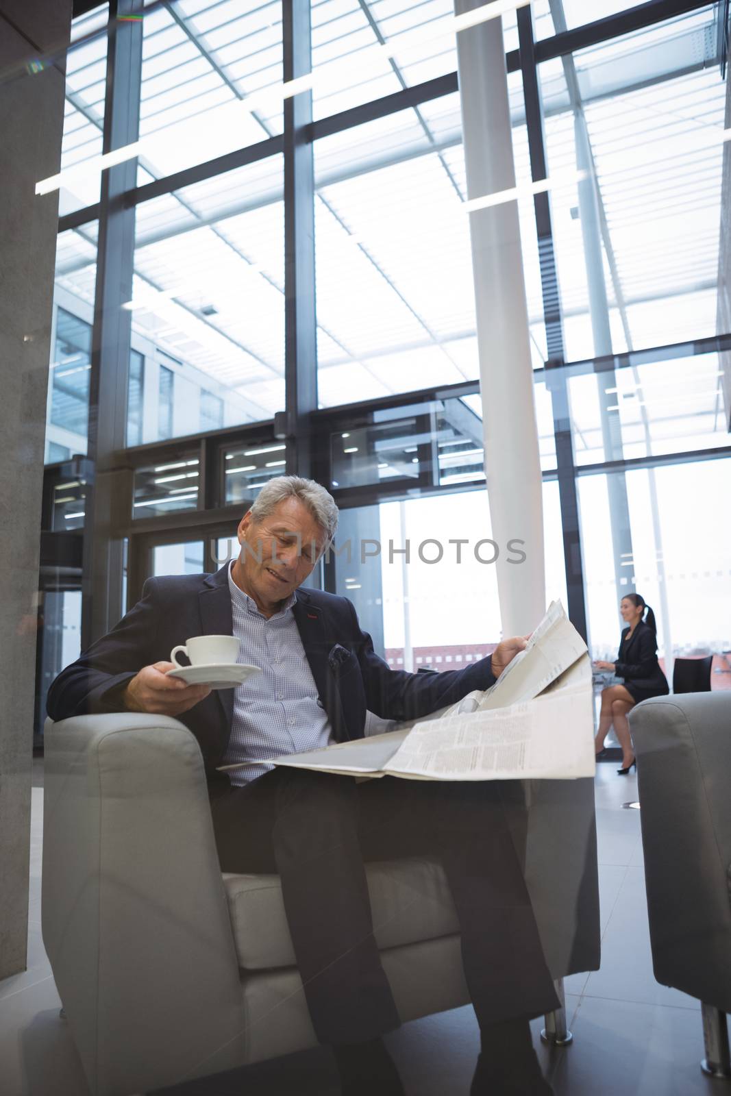 Businessman reading newspaper while having coffee in office