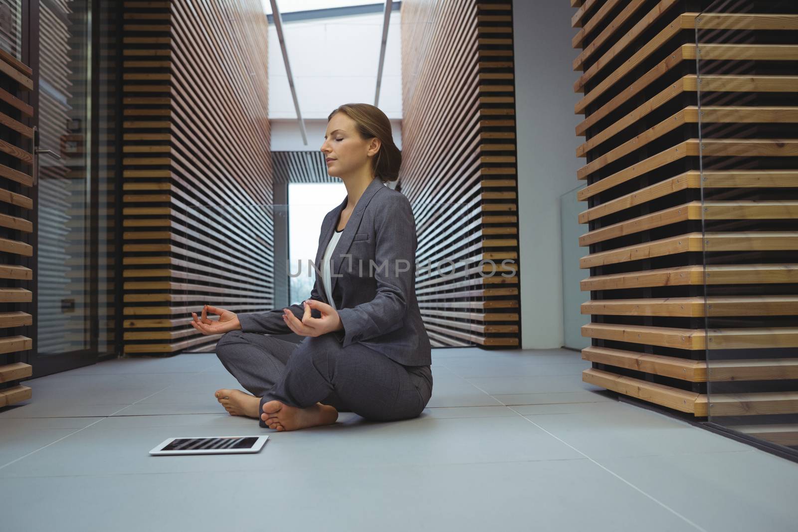 Businesswoman performing yoga in the corridor by Wavebreakmedia