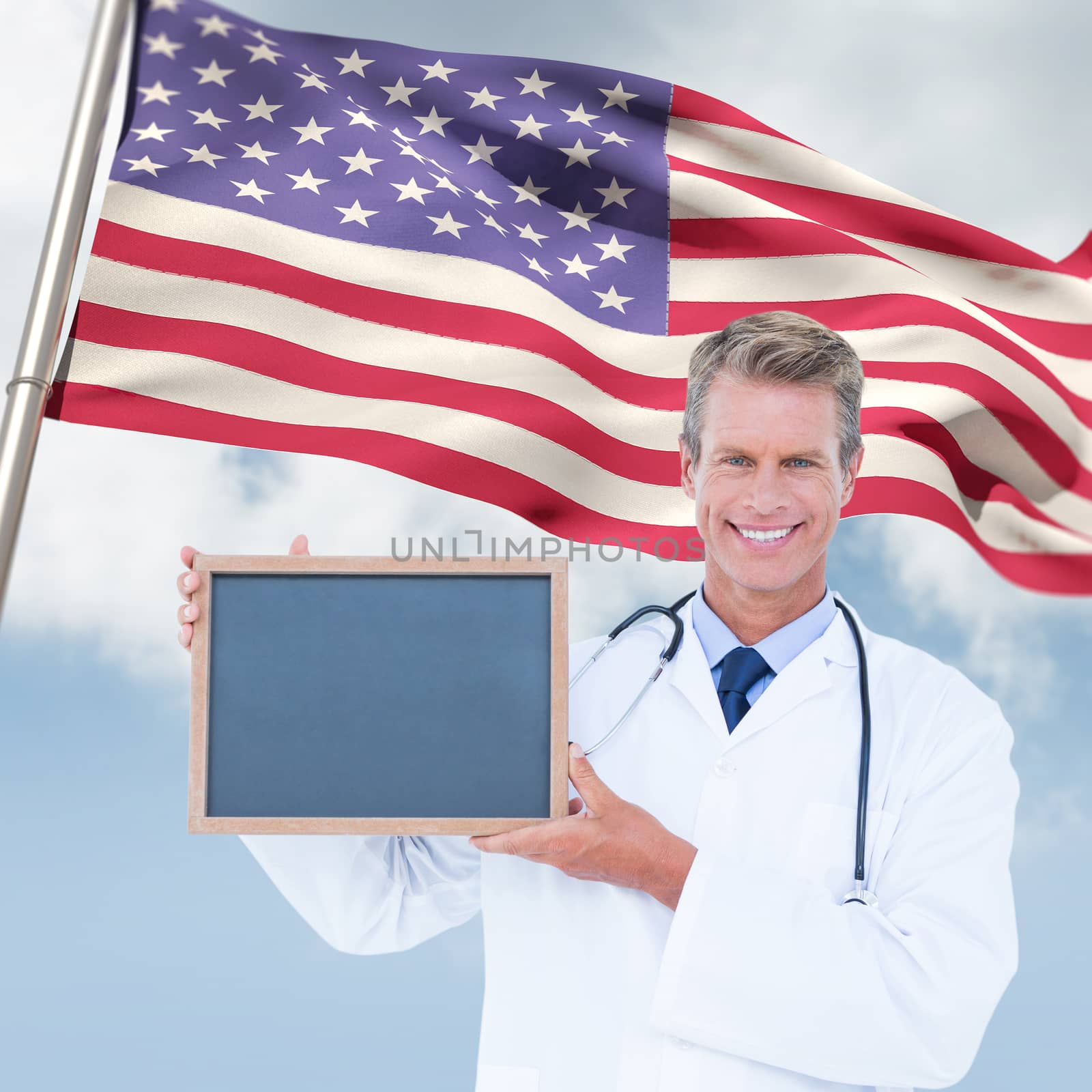 Portrait of smiling male doctor holding blank slate against composite image of low angle view of american flag