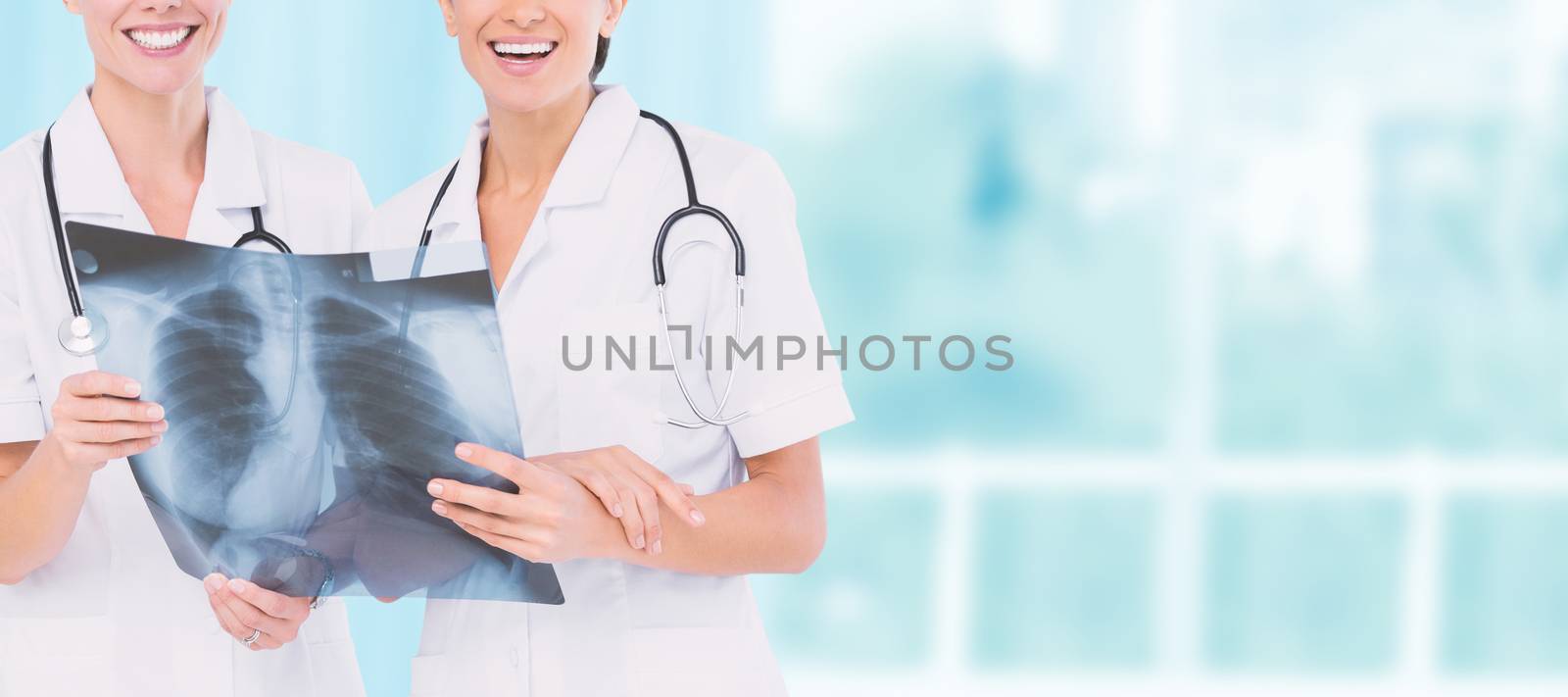 Smiling nurses with xray against dental equipment