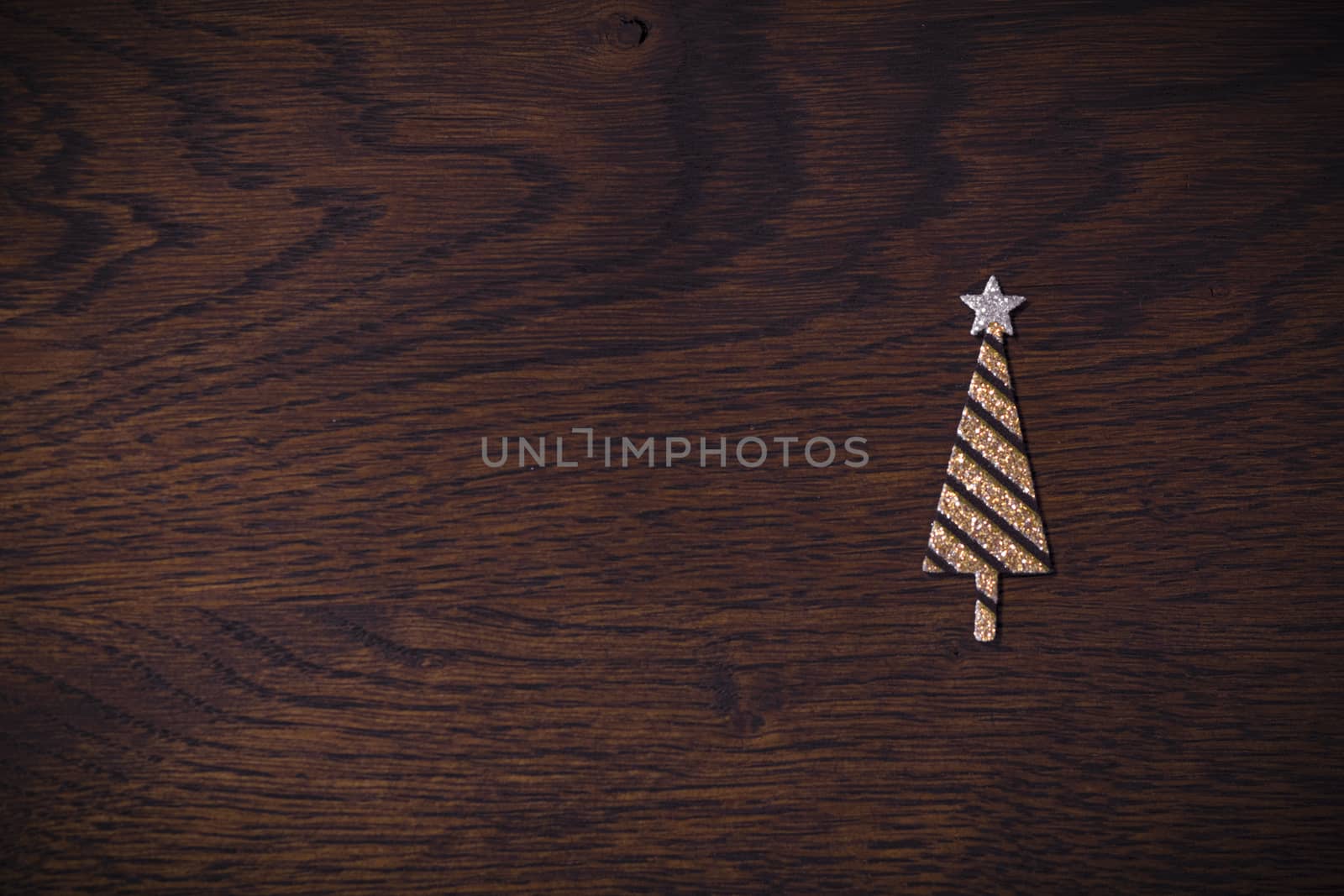 Golden Christmas tree with glitter on a wooden background in brown colors in the Xmas holidays