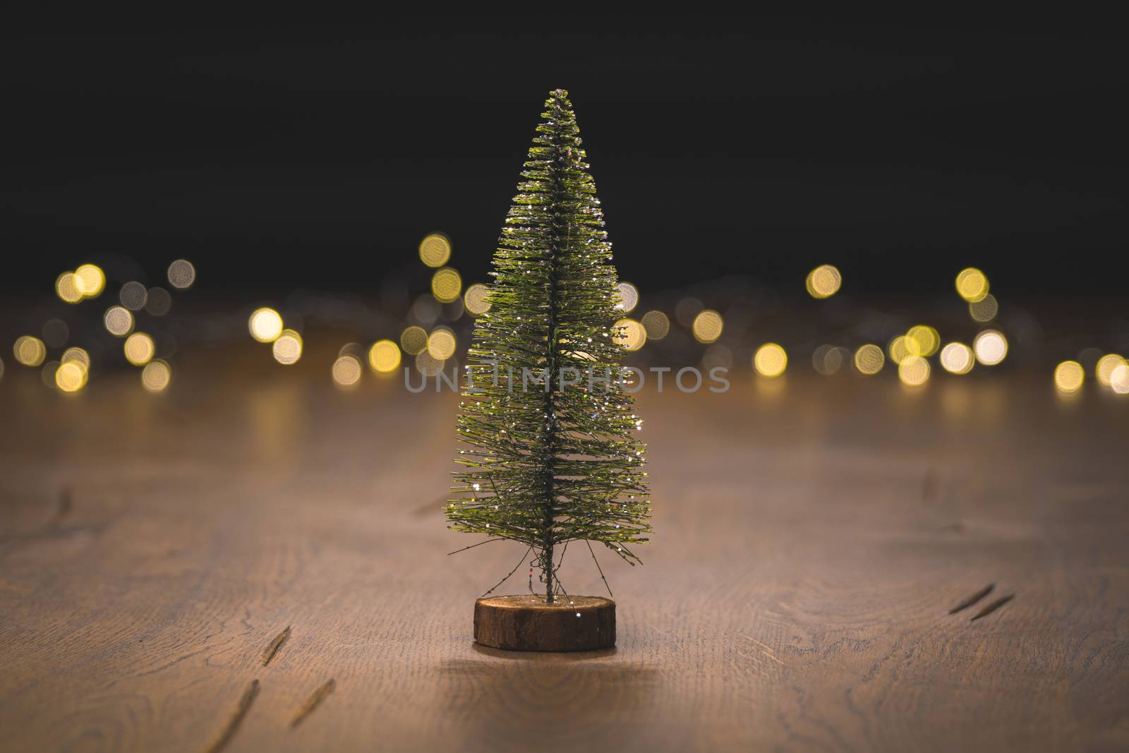 Christmas tree decoration on a wooden surface with golden bokeh lights in the background