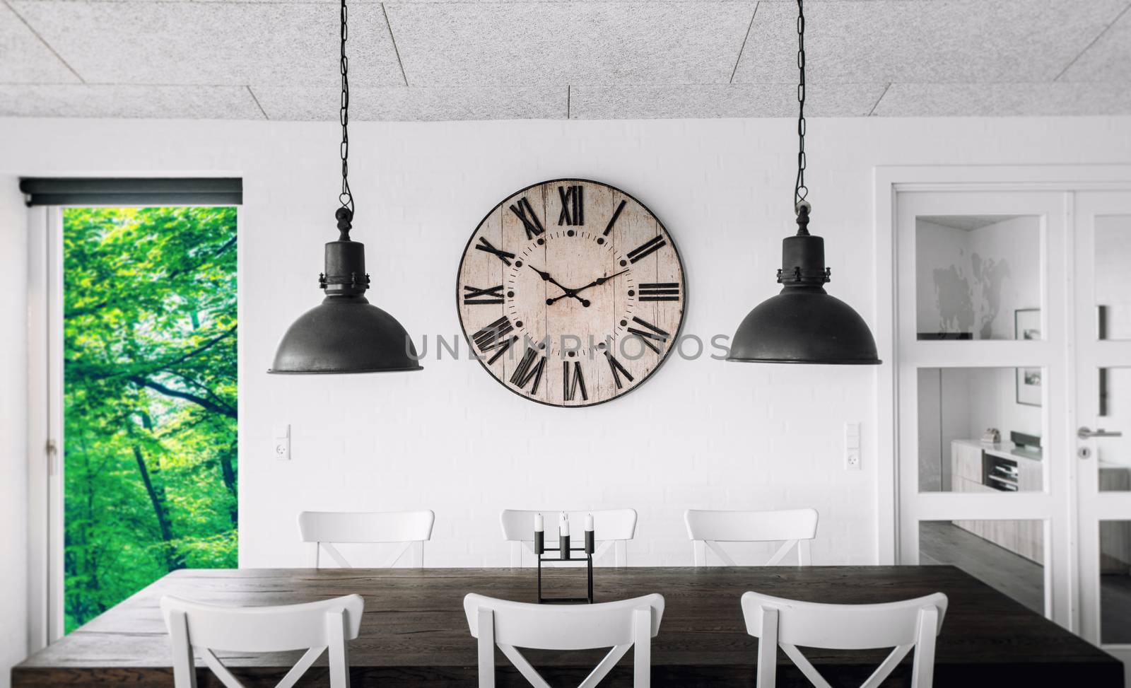 Retro clock over a table on a wall in a living room with green trees outside in the spring