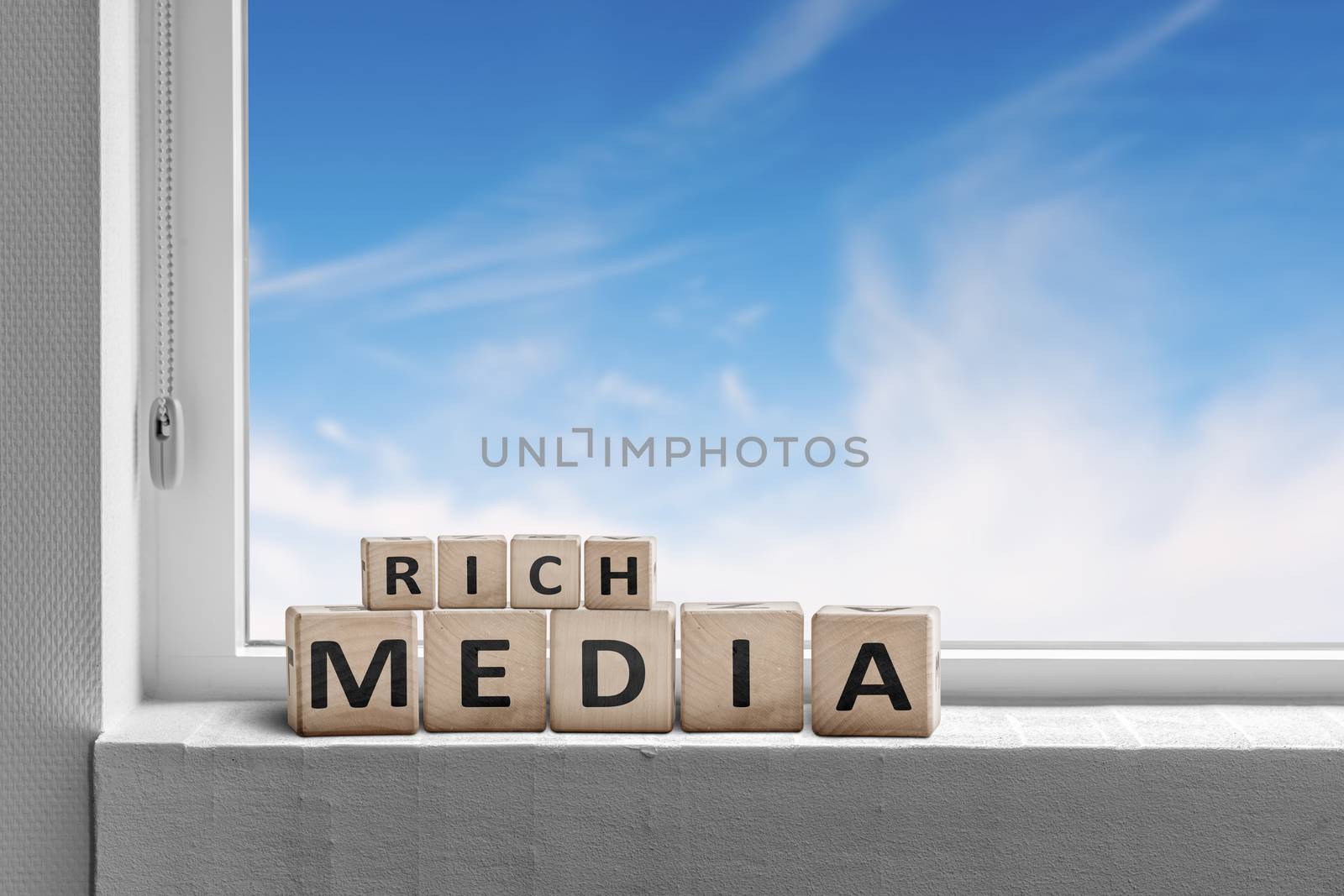 Rich media sign written on wooden blocks in a window with a blue sky outside