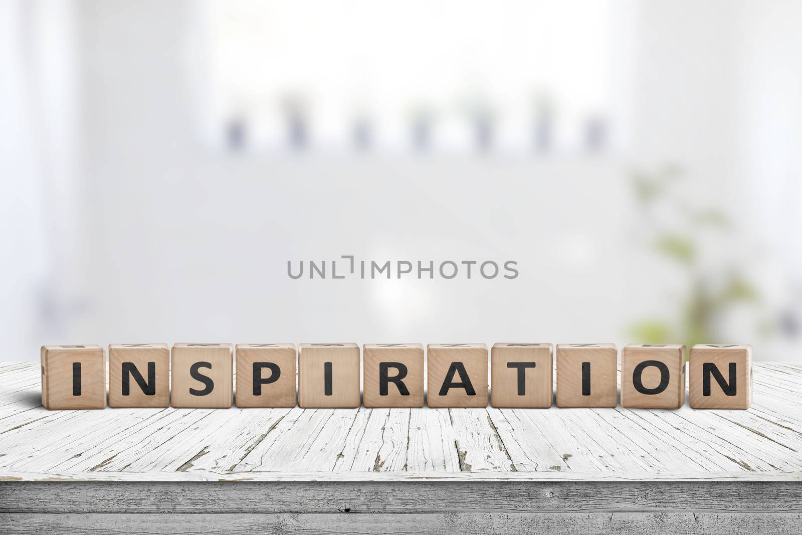 Inspiration sign on a wooden table in a bright room with green plants