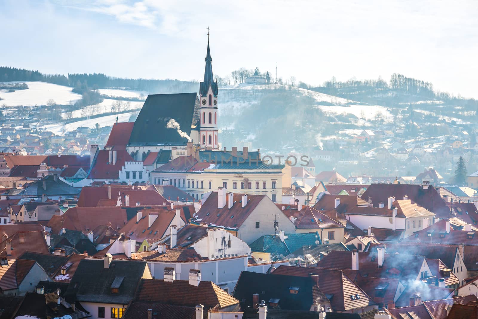 Sunrise view of Cesky Krumlov Saint Vitus church in winter and the small town surrounding it. Snow covered Rooftops with smoking chimneys. by petrsvoboda91