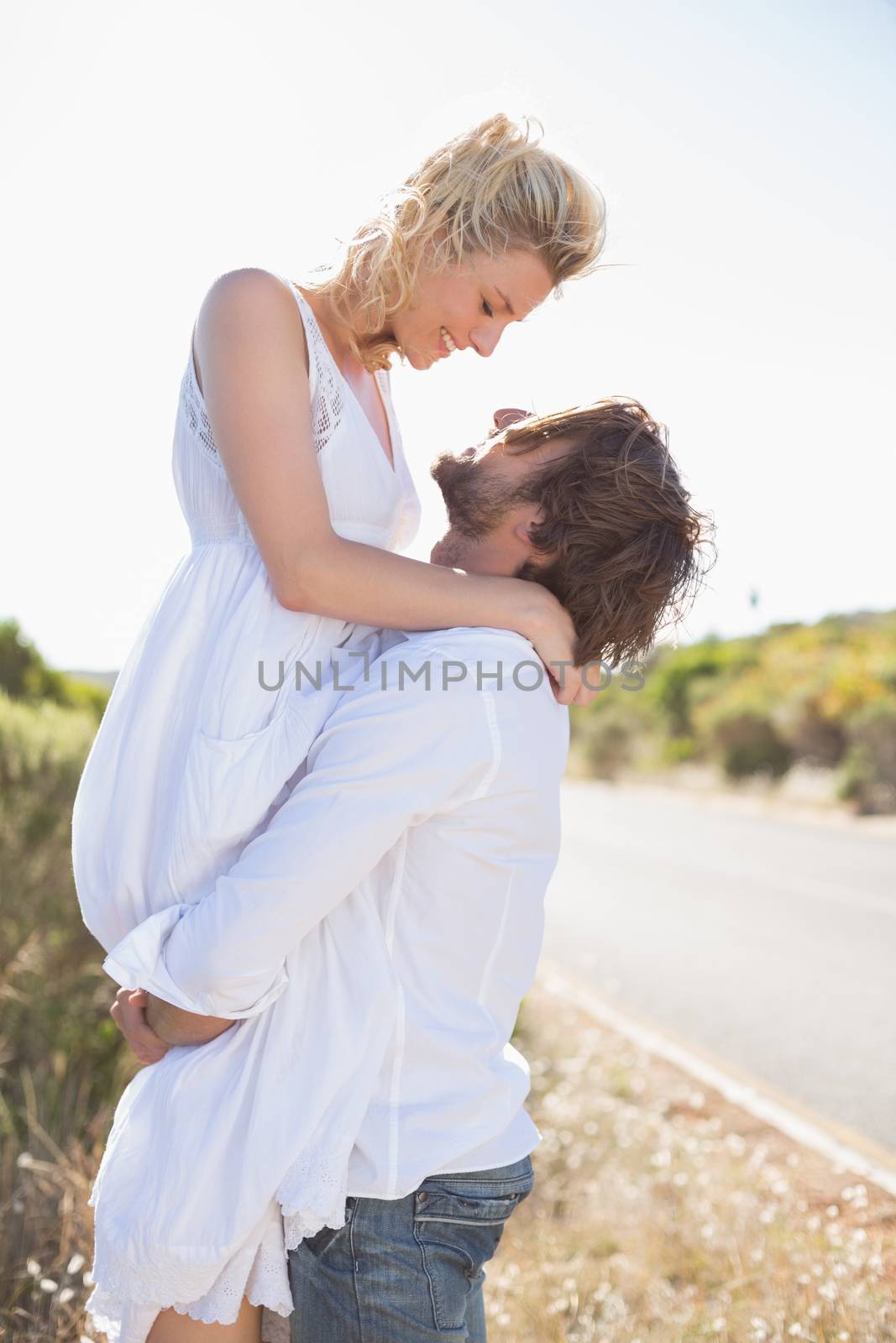 Attractive man lifting up his girlfriend on a sunny day