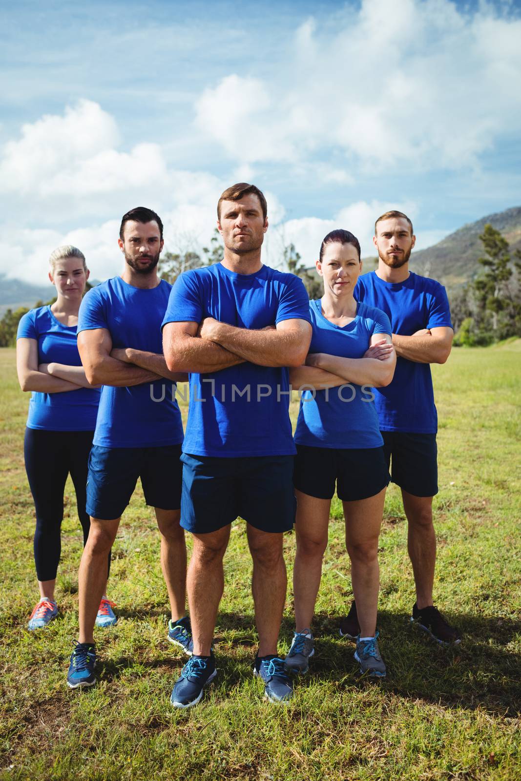 Group of fit people together with arms crossed in a boot camp by Wavebreakmedia