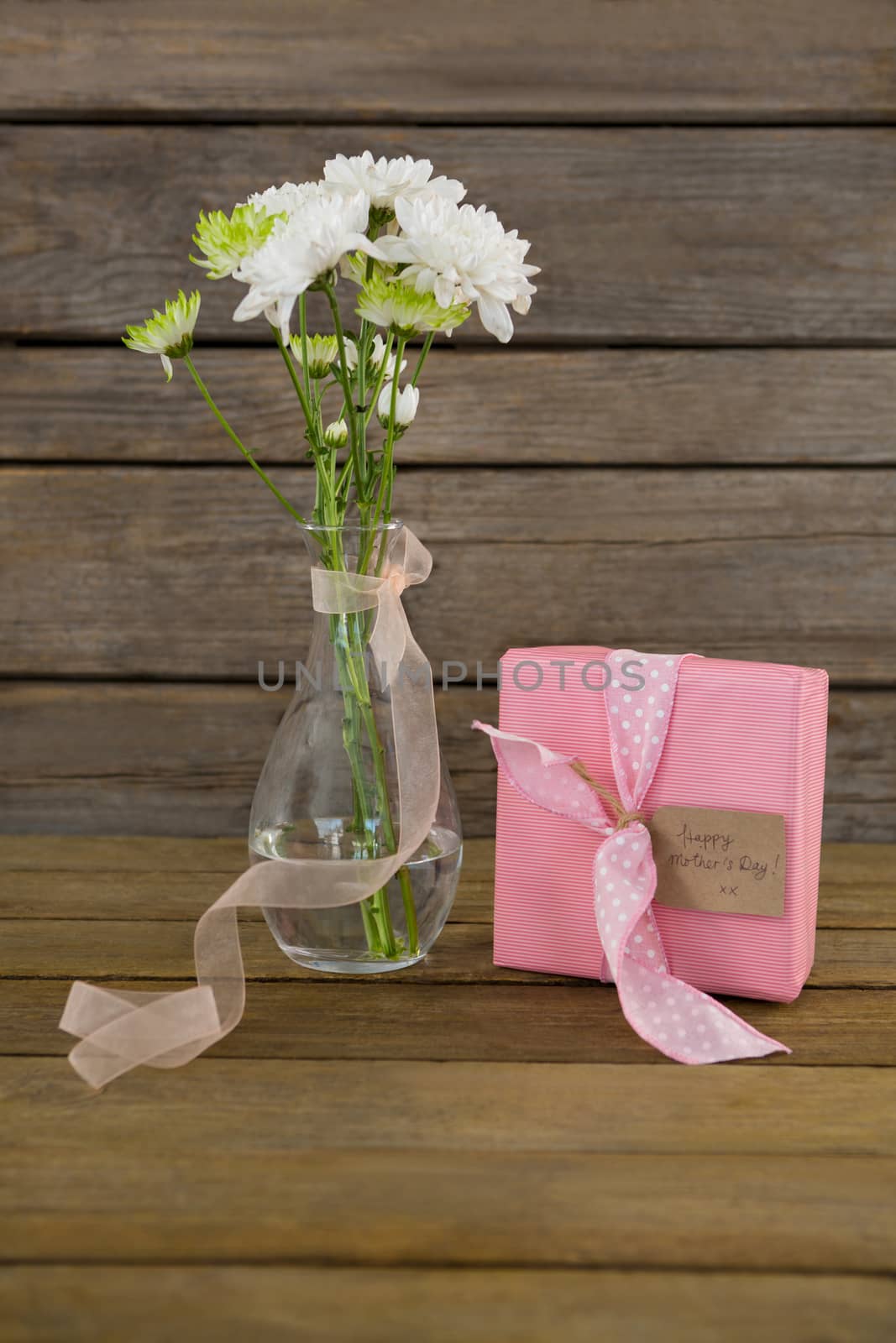 Gift box and flower vase on wooden surface by Wavebreakmedia
