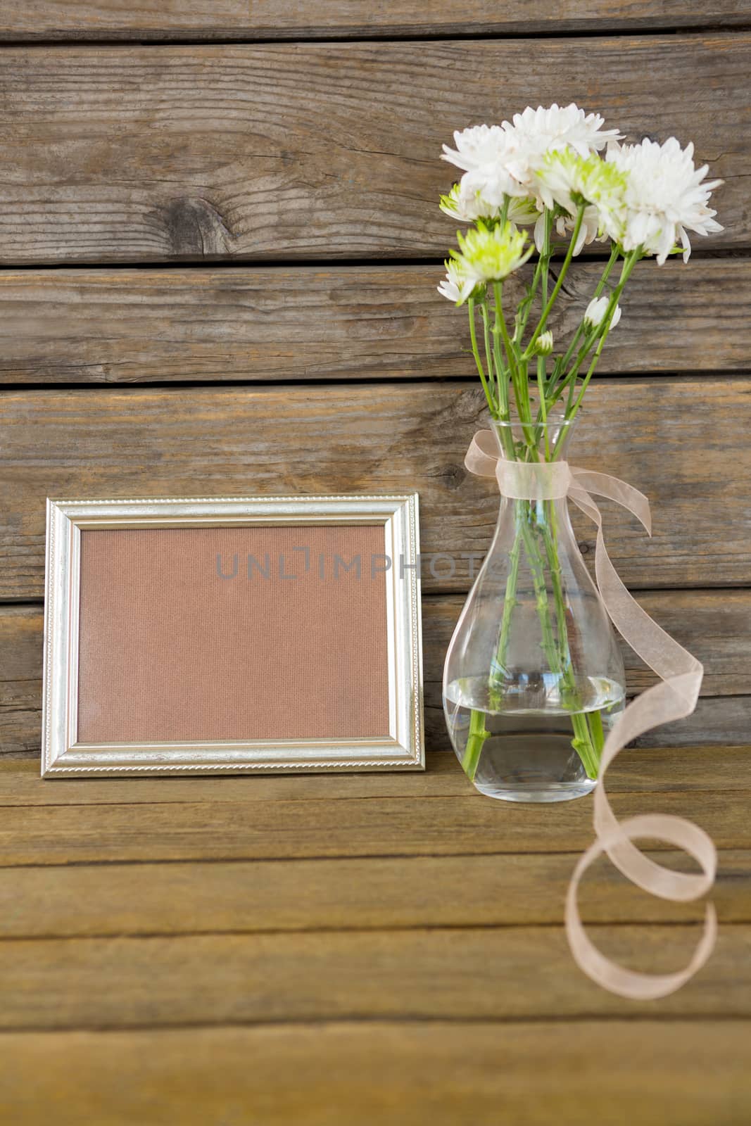 Close-up of photo frame and flower vase on wooden surface