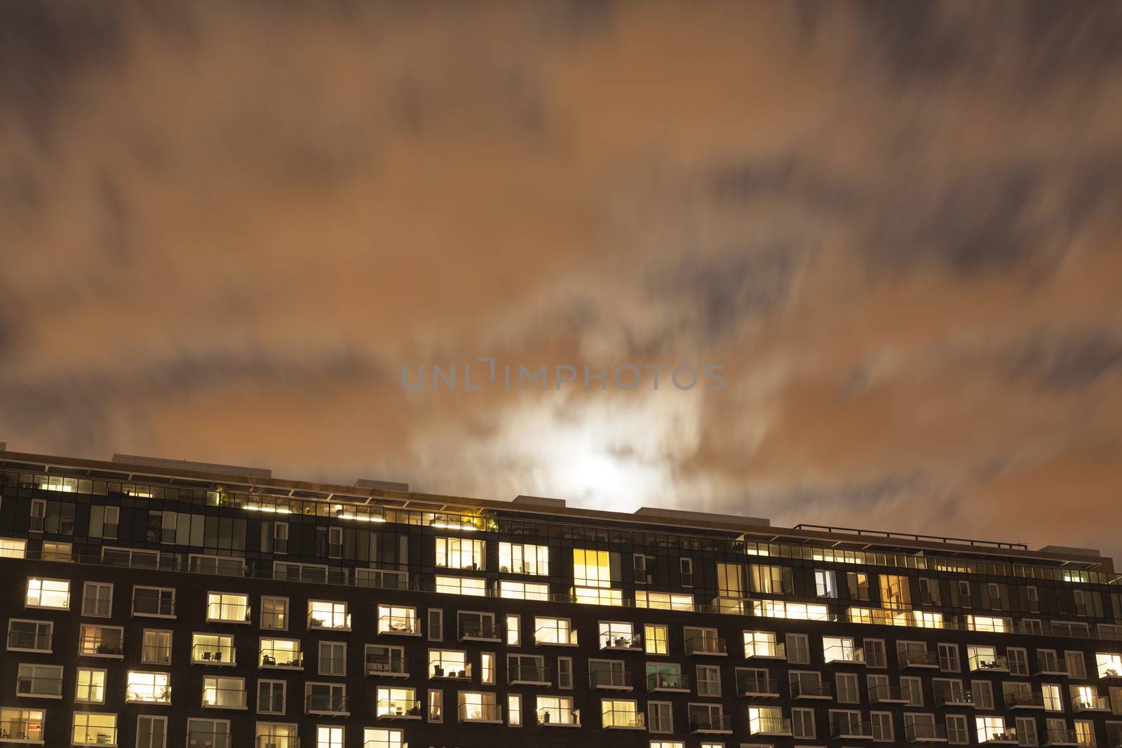 Moon rising over a modern apartment building at dusk