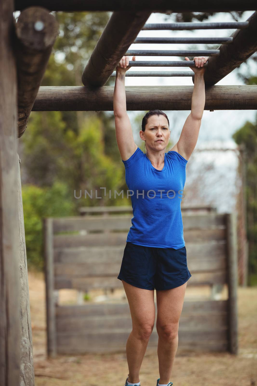 Fit woman climbing monkey bars in bootcamp