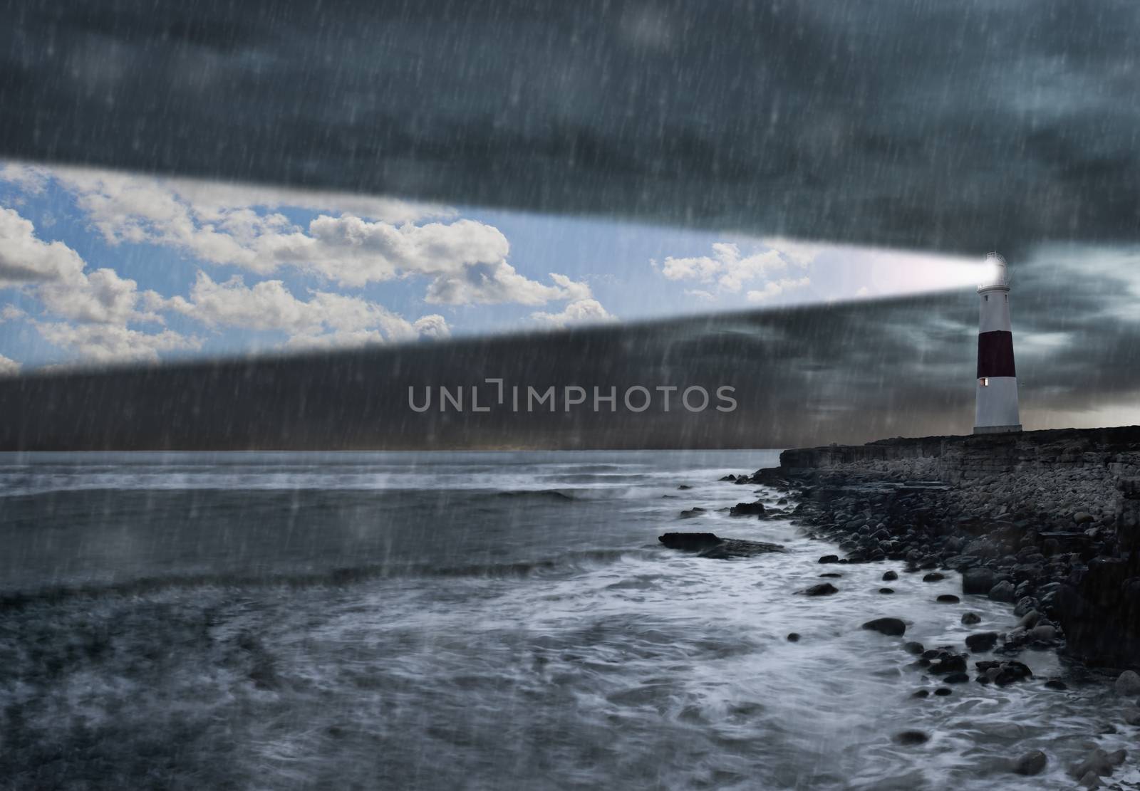Lighthouse emitting beam of blue sky and clouds in a storm by conceptualmotion