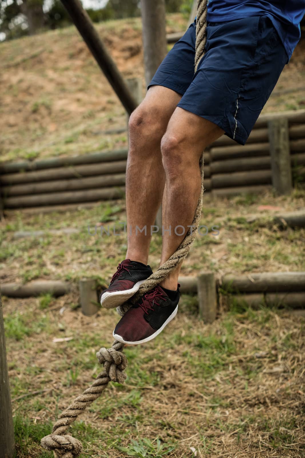 Low section of man climbing a rope during obstacle course by Wavebreakmedia