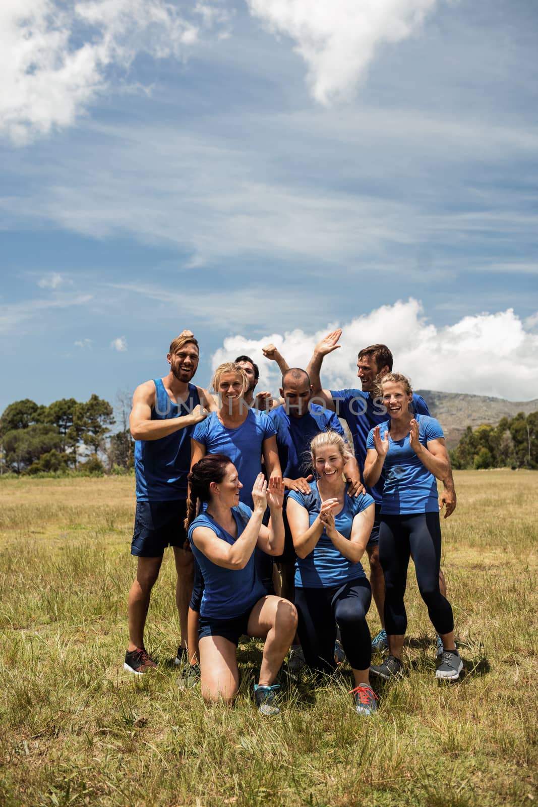 Group of fit people cheering together in boot camp on sunny day