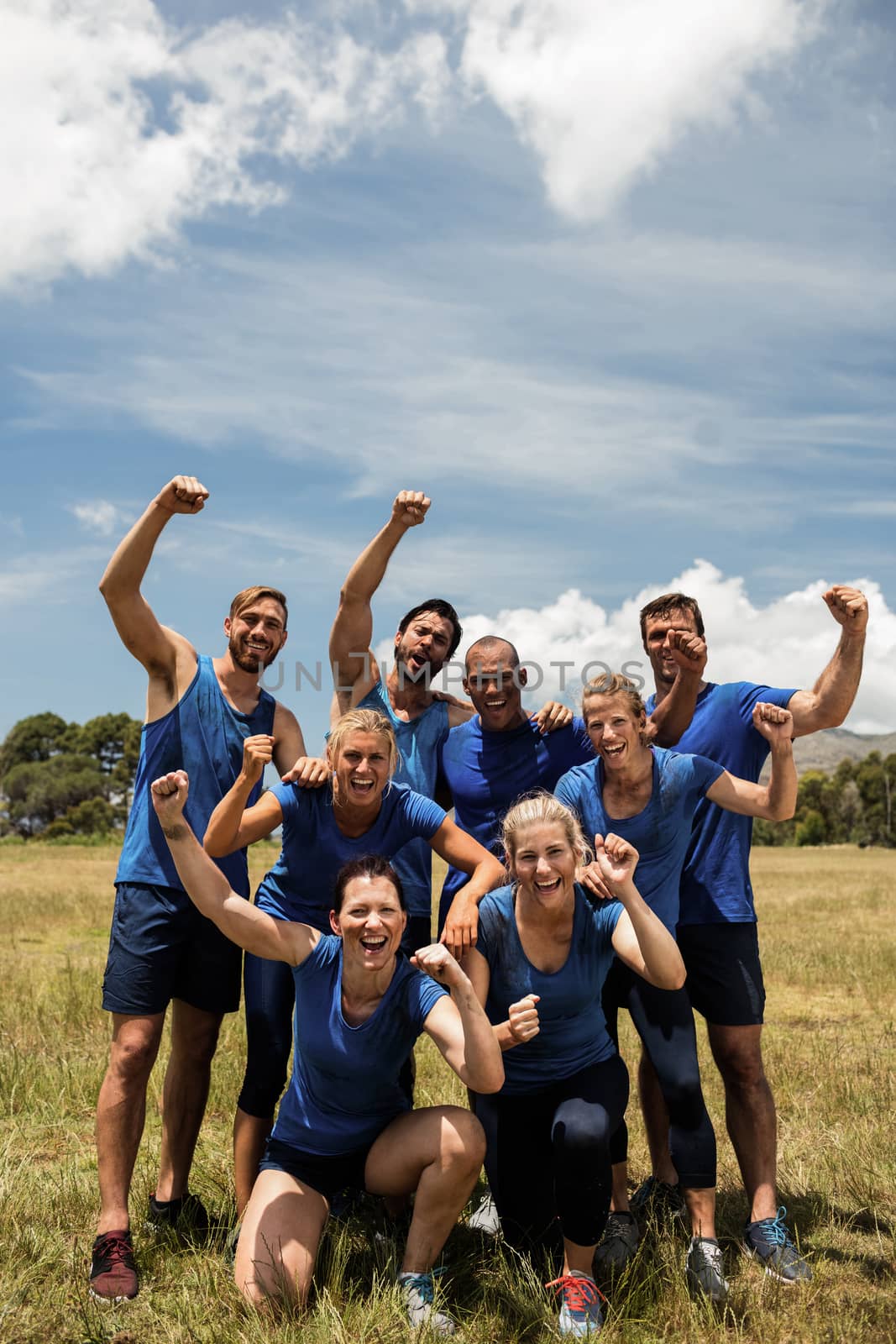 Group of fit people posing together in boot camp on a sunny day