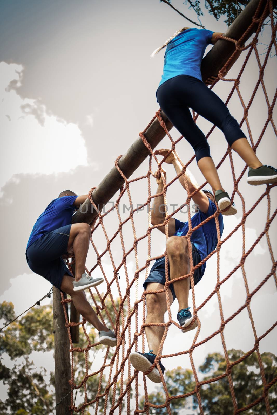 People climbing a net during obstacle course by Wavebreakmedia