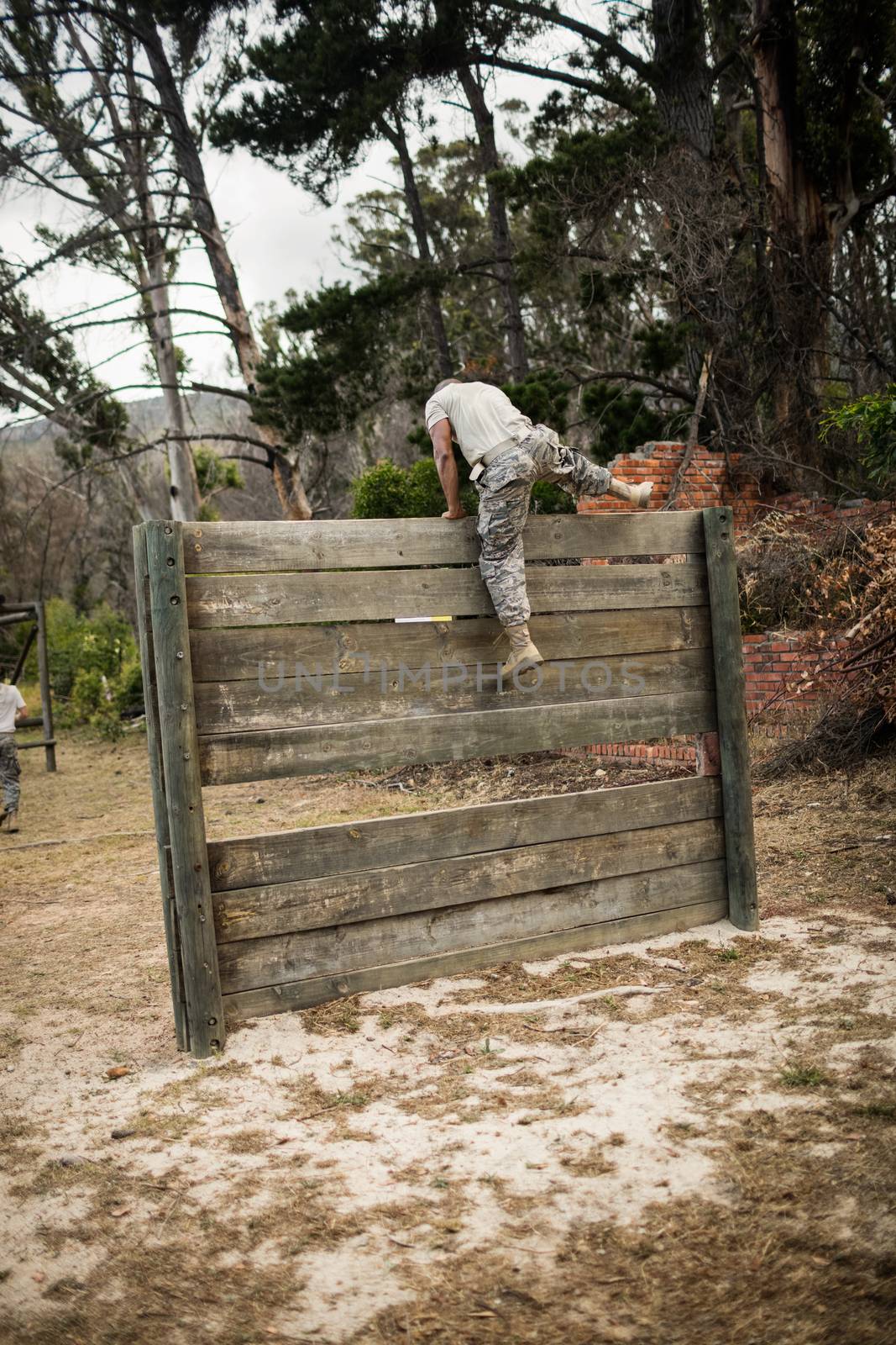 Rear view of soldier climbing wooden wall in boot camp