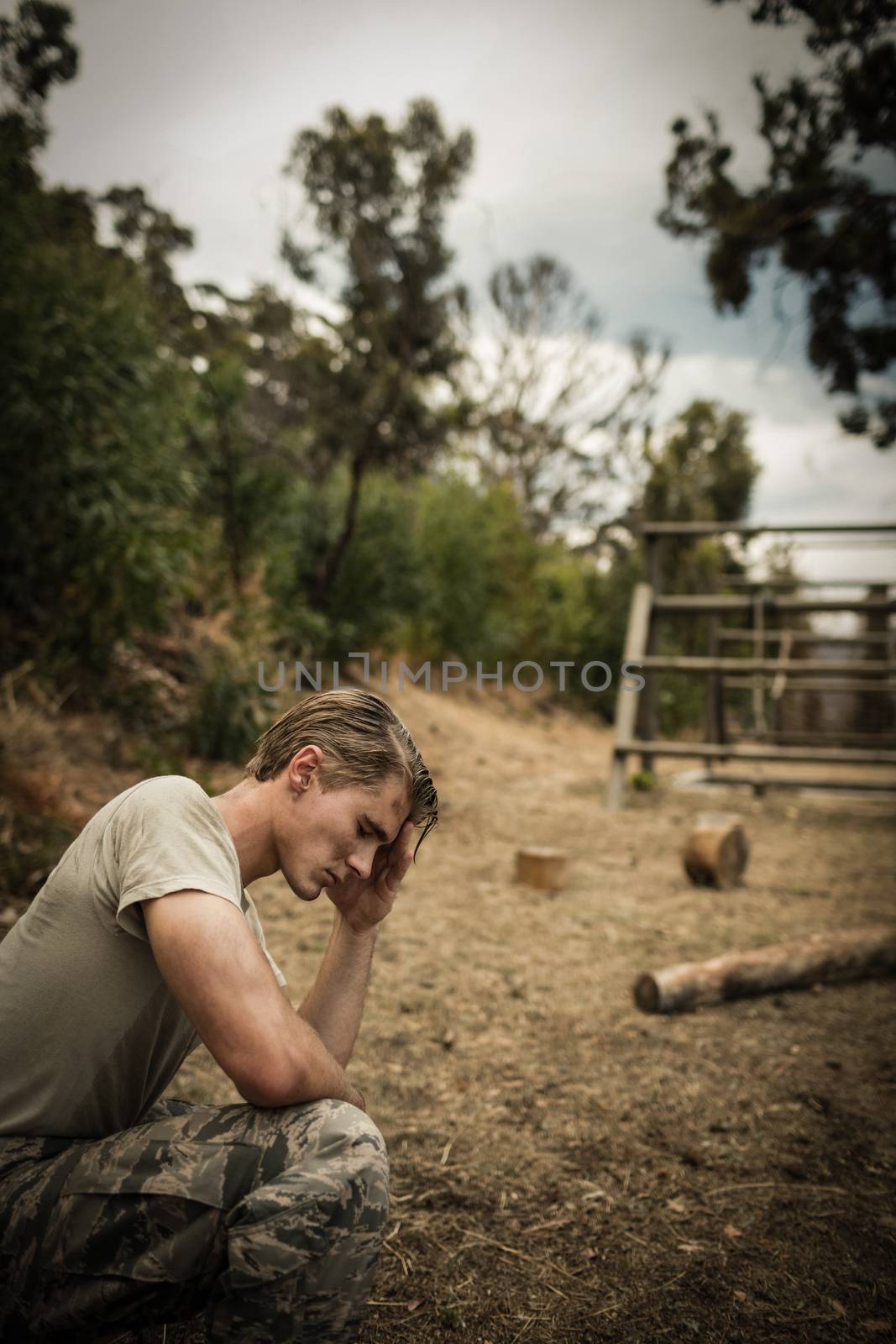 Tired soldier with hand on head sitting  by Wavebreakmedia